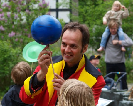 Ein Mann in einem bunten Kostüm jongliert mit einem Ball.