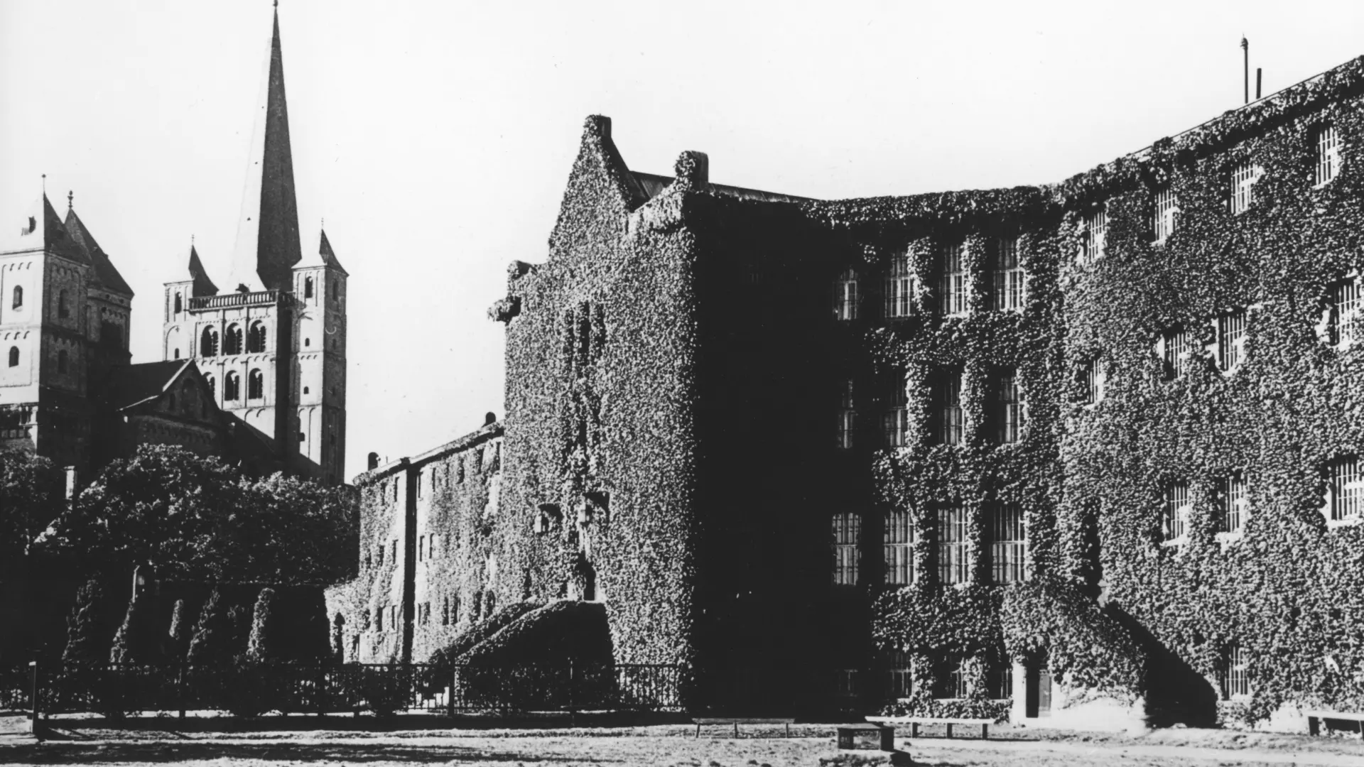 Schwarz-weiß Foto des Zellengebäudes, im Hintergrund die Abteikirche
