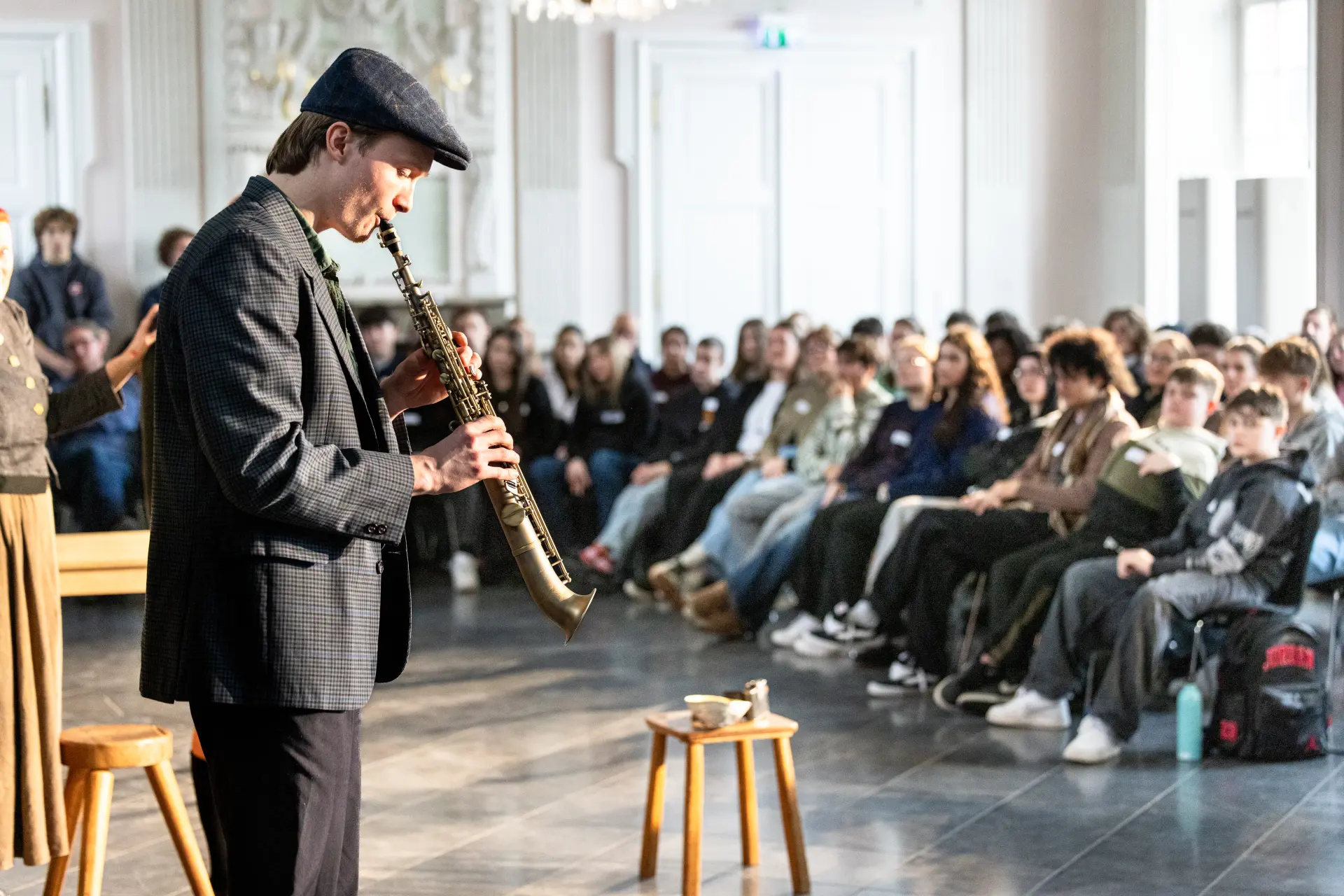 Foto von einem Instrument spielenden Mann und Publikum im Hintergrund