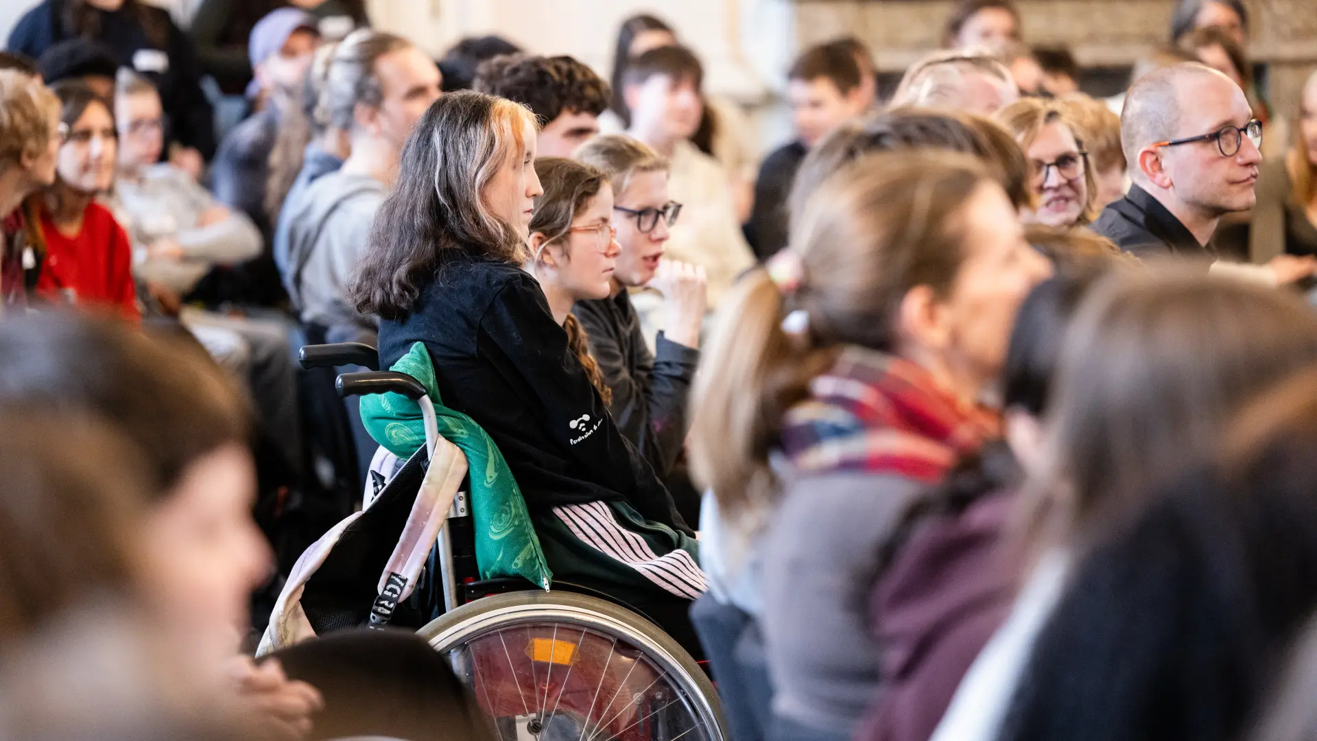 Foto von Schüler*innen, u.a. im Rollstuhl, bei einer Veranstaltung im Kaisersaal