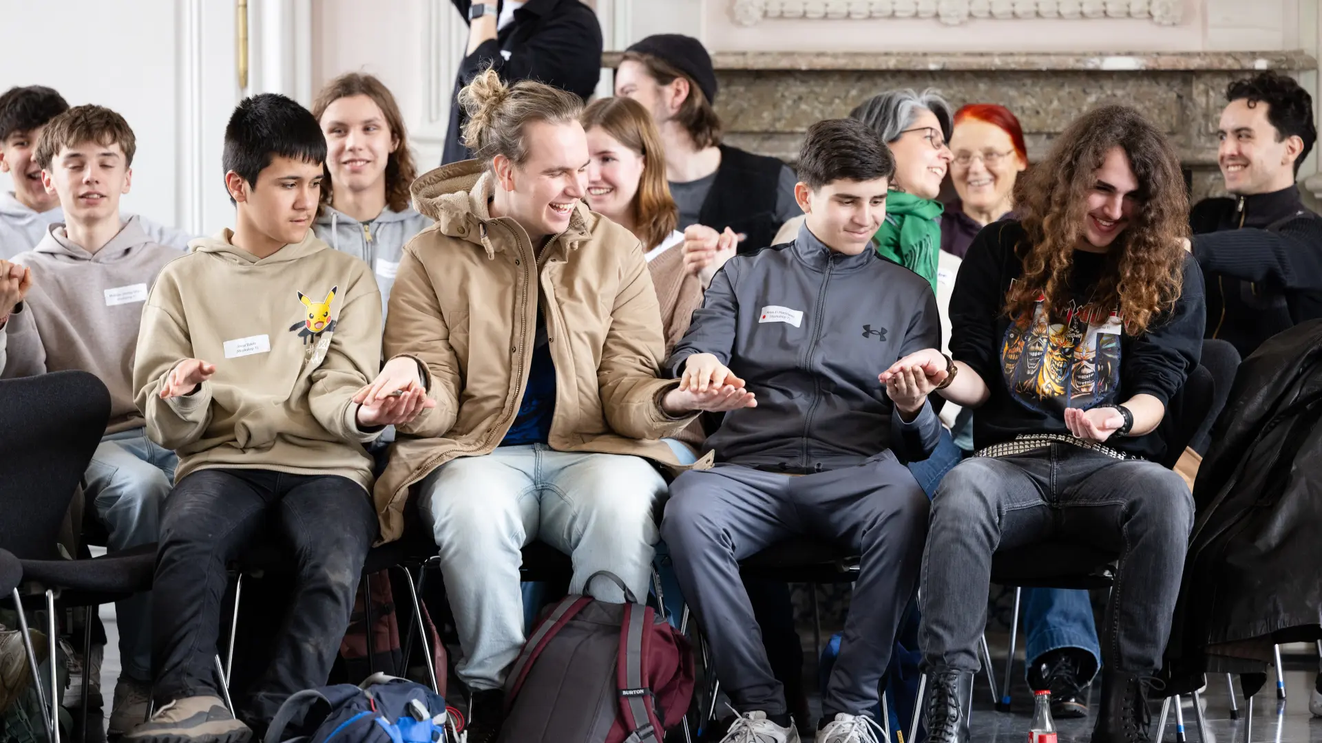 Foto von Jugendlichen, die in einer Stuhlreihe sitzen und sich die Hände halten