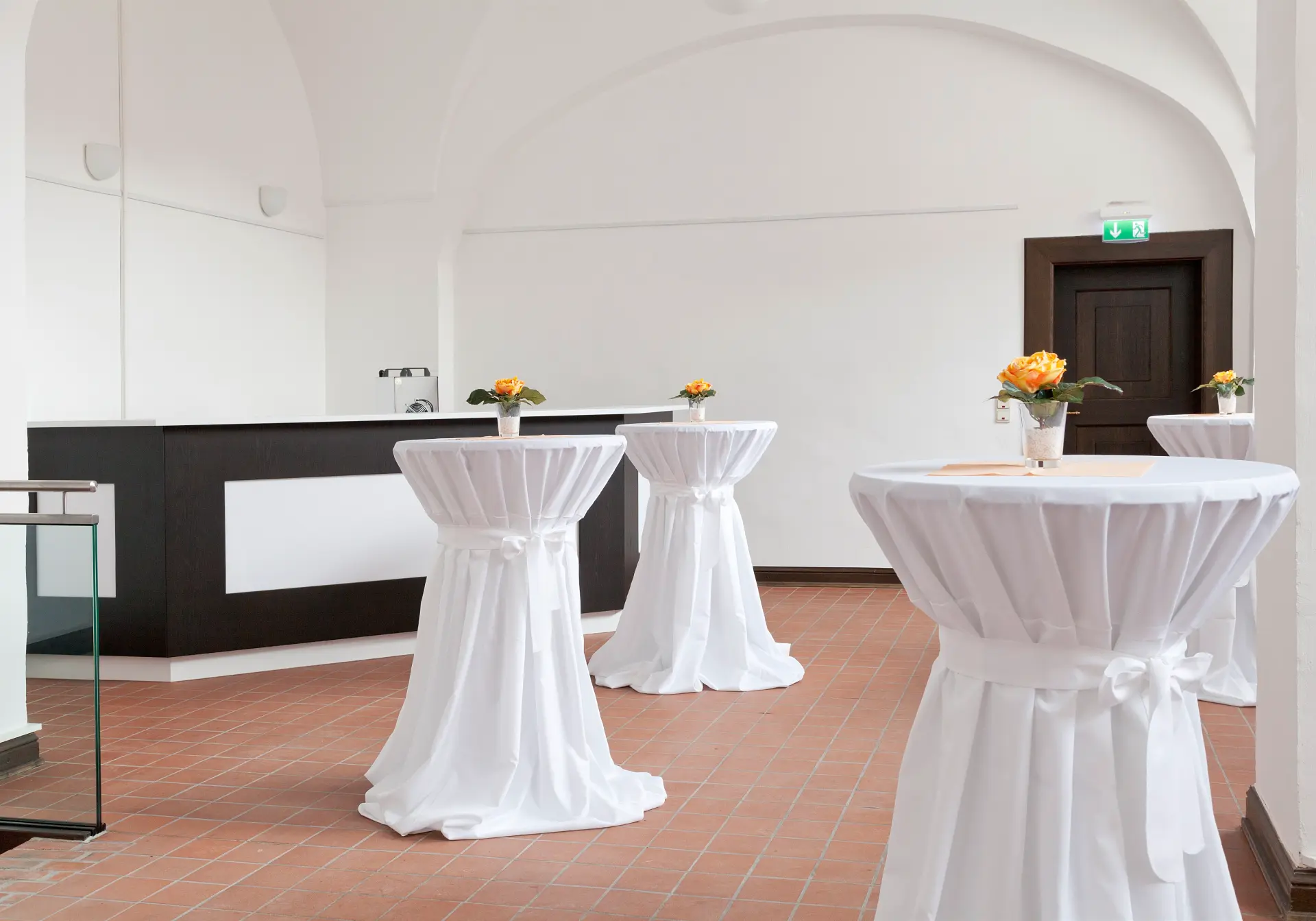 Foto von Stehtischen mit Blumendeko vor einer Bar