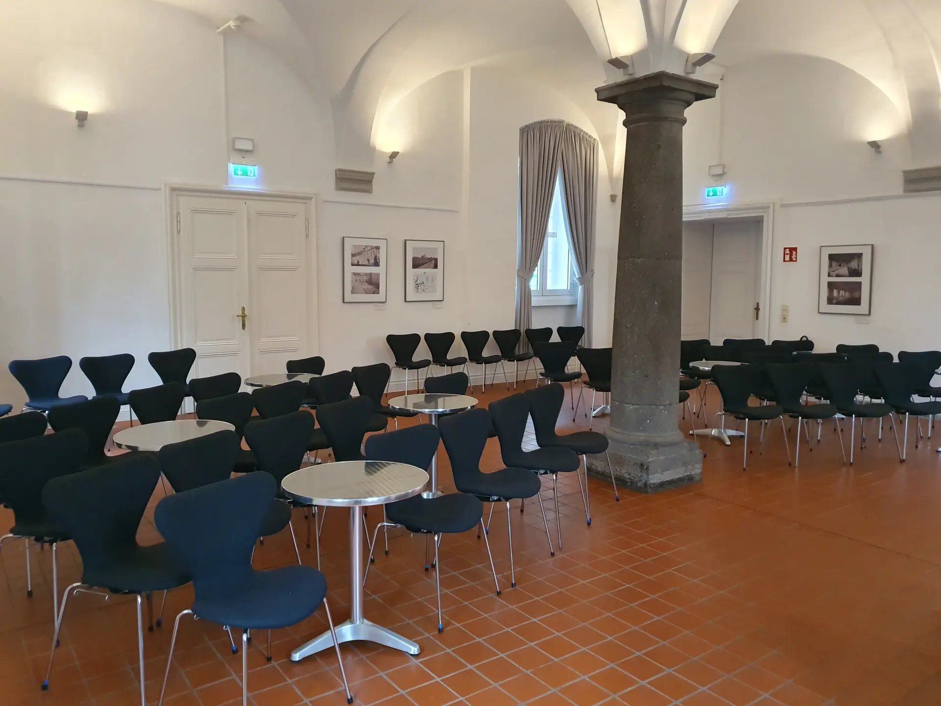 Foto von Stuhlreihen und kleinen Tischen in Gewölbesaal