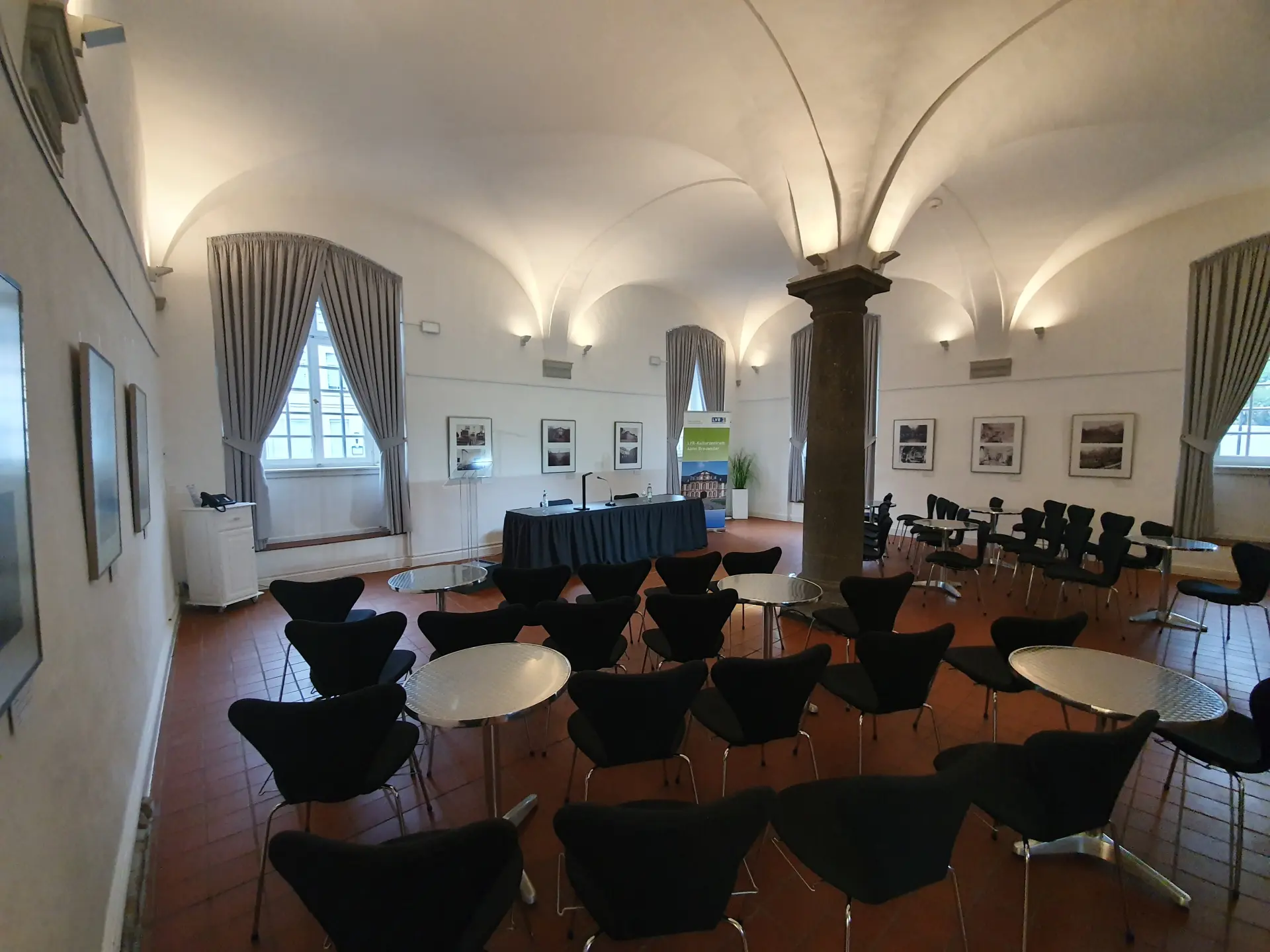 Foto von Stuhlreihen und kleinen runden Tischen im Gewölbesaal
