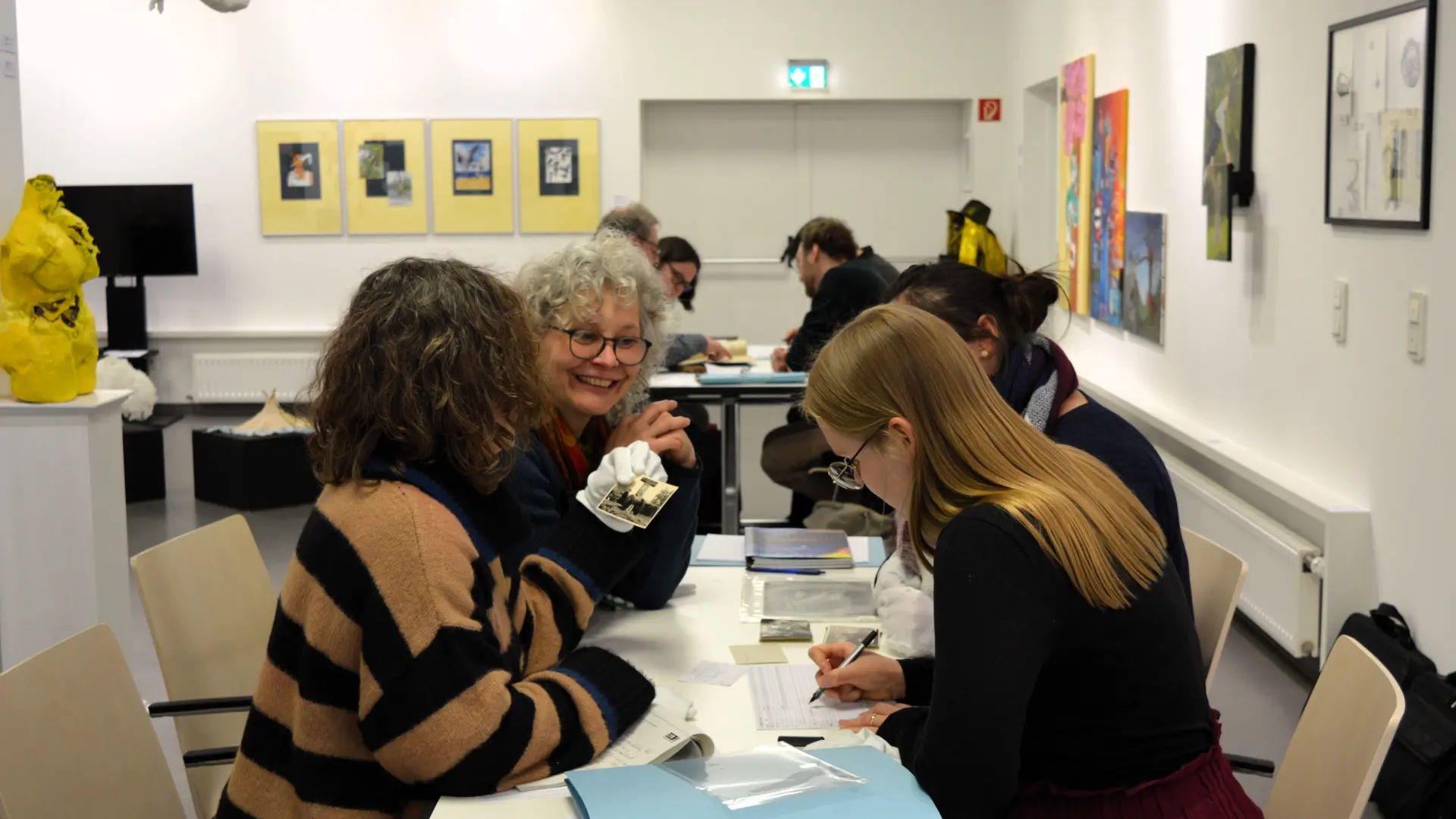 Foto von drei Frauen, die bei einer archivischen Erschließungsübung an einem Tisch sitzend diskutieren.
