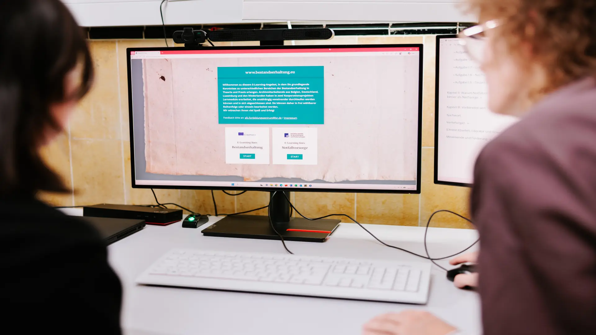 Foto von zwei Personen, die auf einen Computerbildschirm mit dem E-Learning-Kurs Bestandserhaltung blicken.