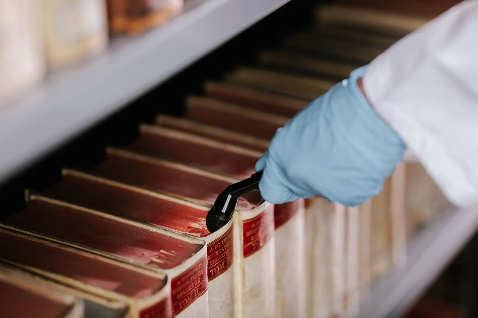 Eine Person saugt den Kopfschnitt von Büchern ab