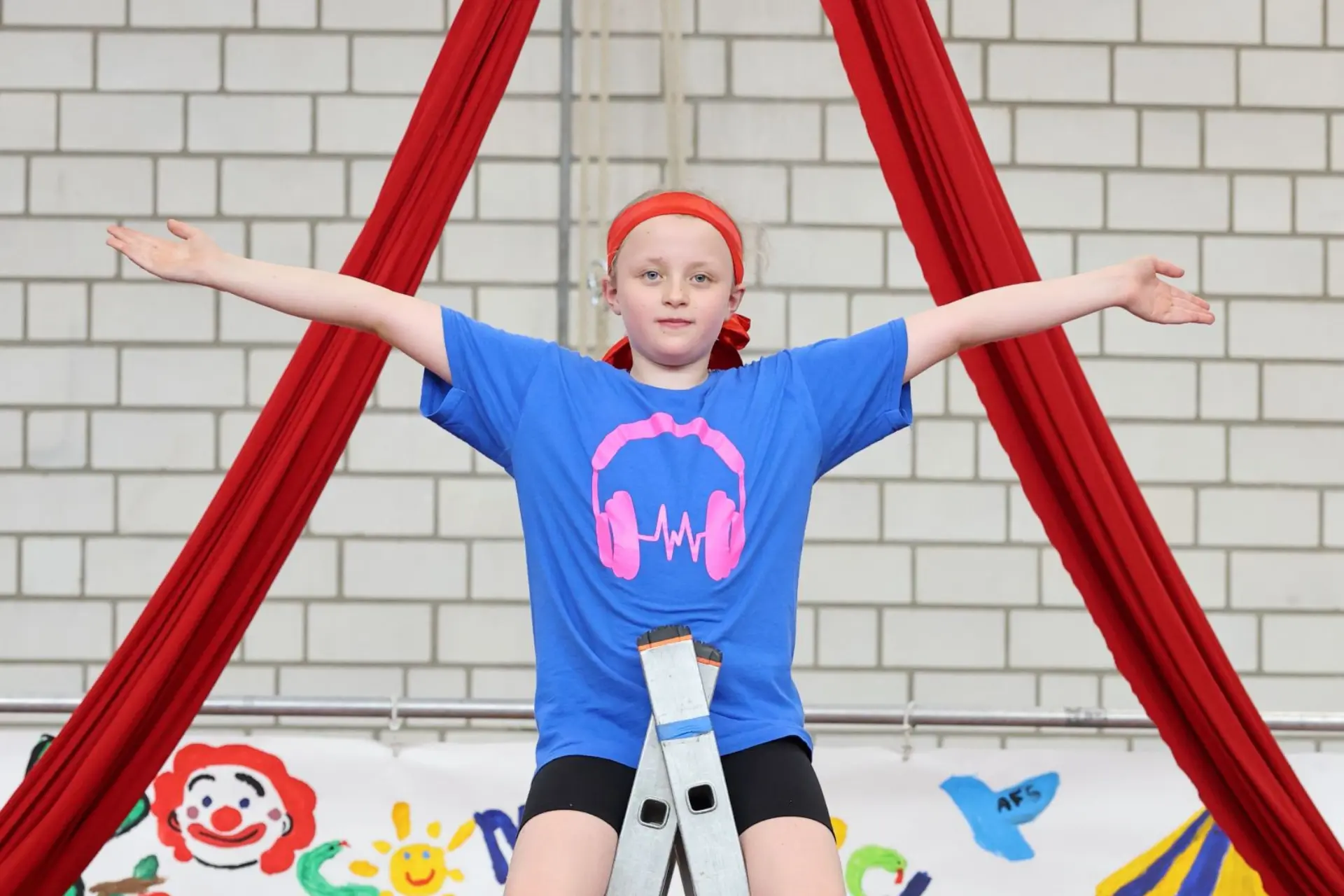 Schülerin macht bei Zirkusaufführung Pose auf der Leiter