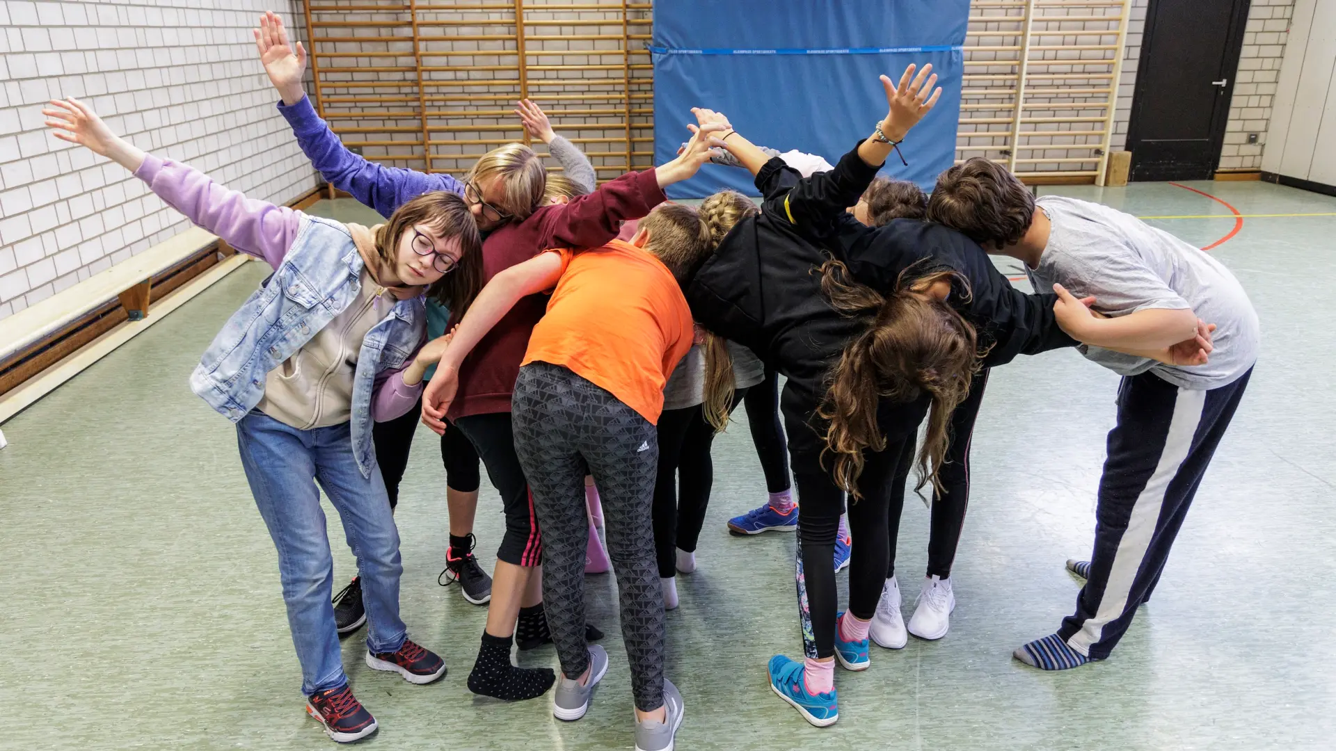 Schüler*innen machen in der Turnhalle eine Gruppenübung