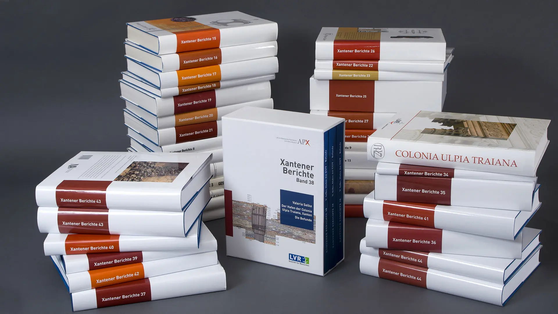 Vier Stapel Bücher der "Xantener Berichte" vor dunklem Studiohintergrund