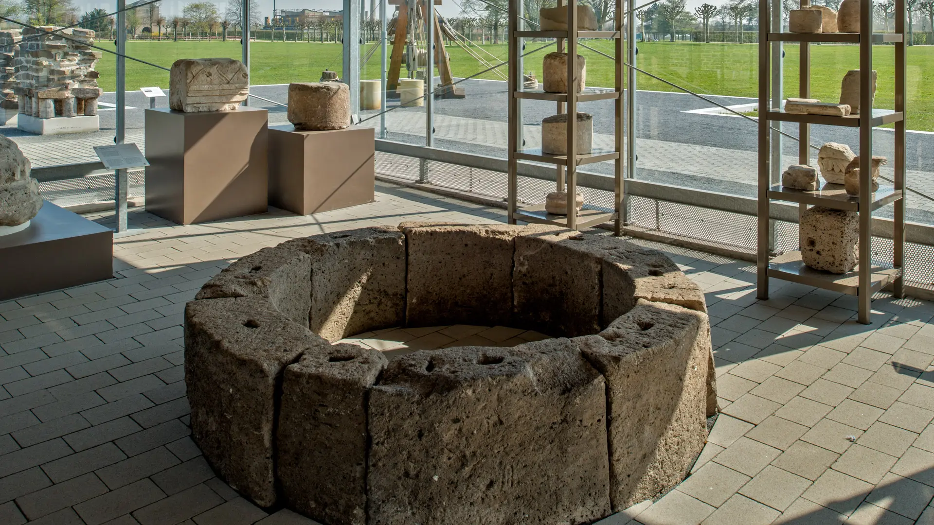 Innenansicht des Pavillons "Bauen und Technik", im Vordergrund eine gemauerte Brunneneinfassung