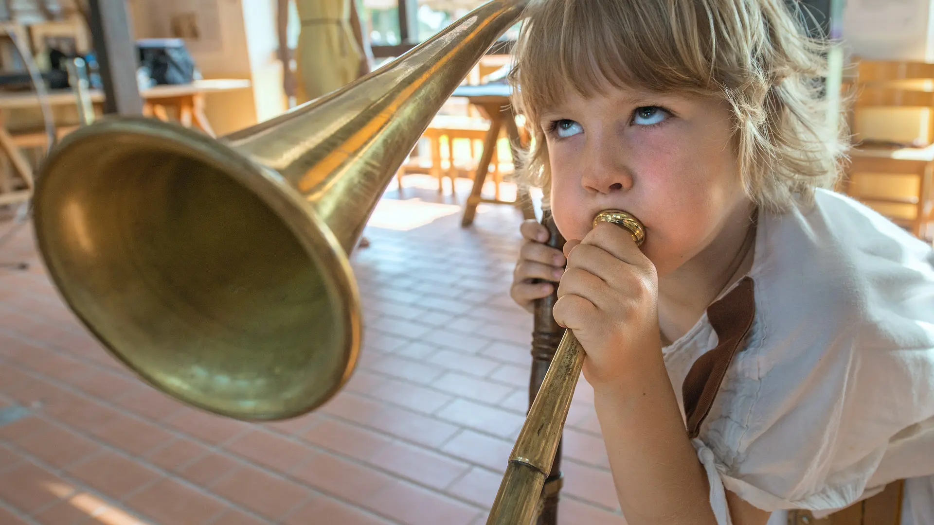 Römerfest, ein Kind in römischer Kleidung pustet aus Leibeskräften in ein Horn