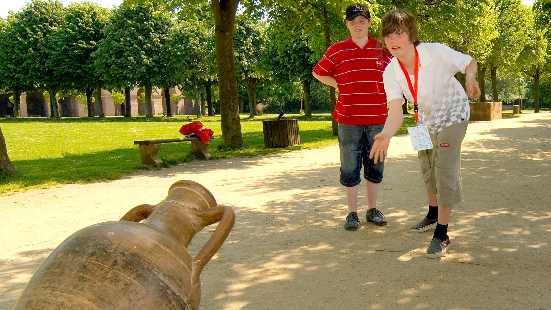 Zwei Kinder versuchen, Walnüsse in den Hals einer Amphore zu werfen