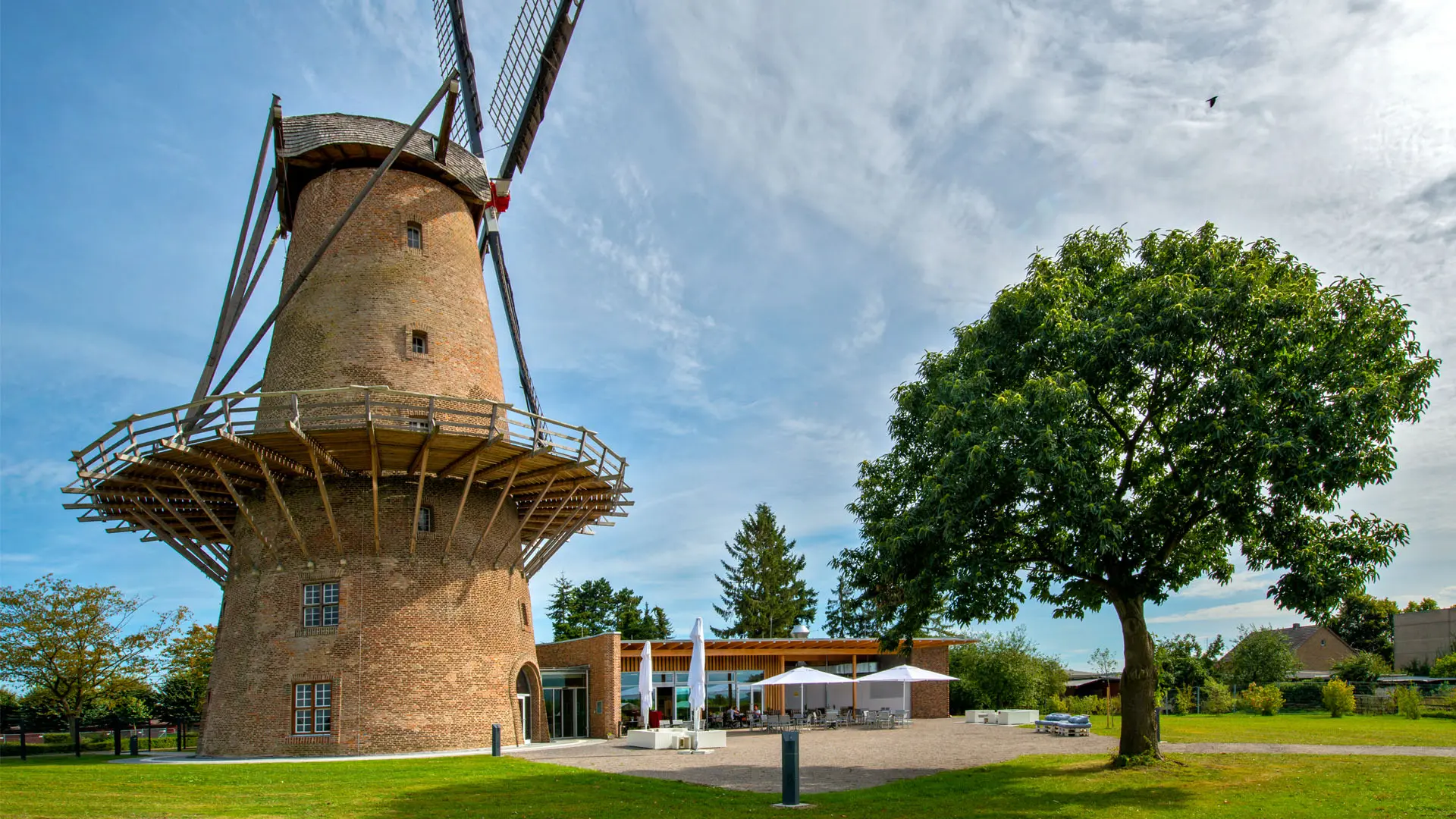 Gruppe von mehreren Erwachsenen um einen Display-Tisch des Limespavillons versammelt, Reiseleiterin in Erklär-Geste