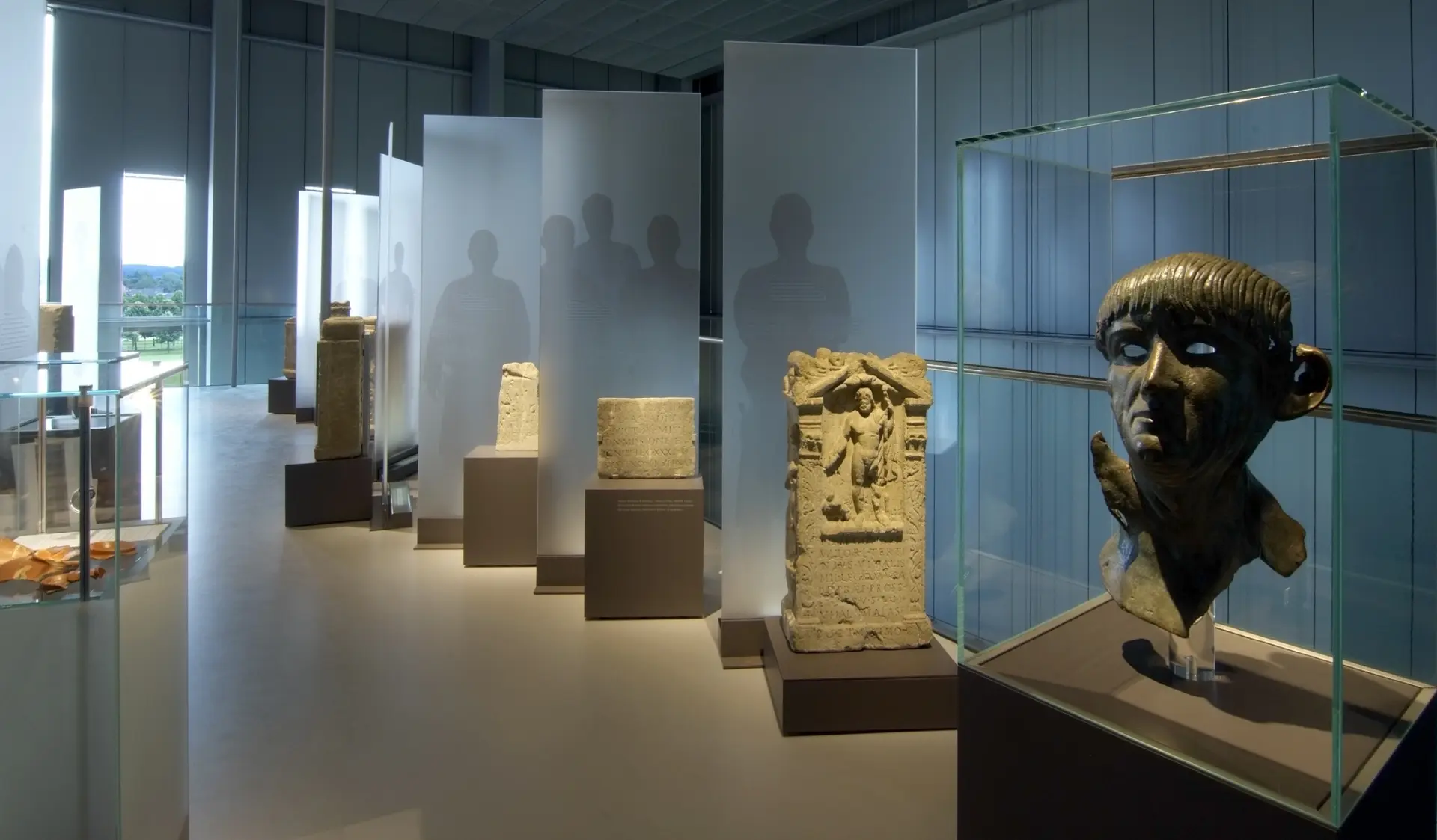 Galerie im Römermuseum mit Grabsteinen und einem Büstenfragment