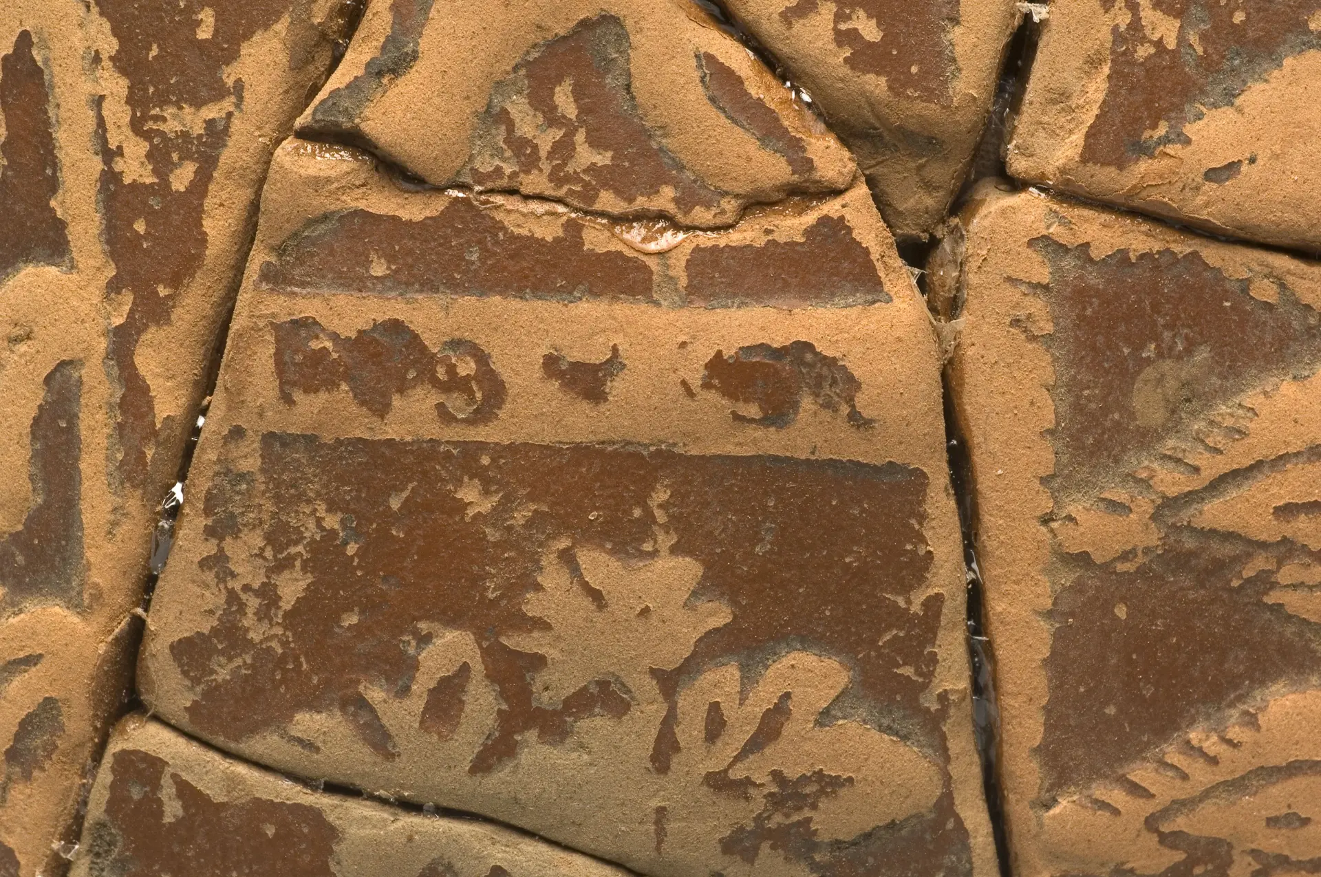 Nahansicht von zusammengesetzten Keramikscherben. Der Ton ist rot und die Oberfläche ist verziert.