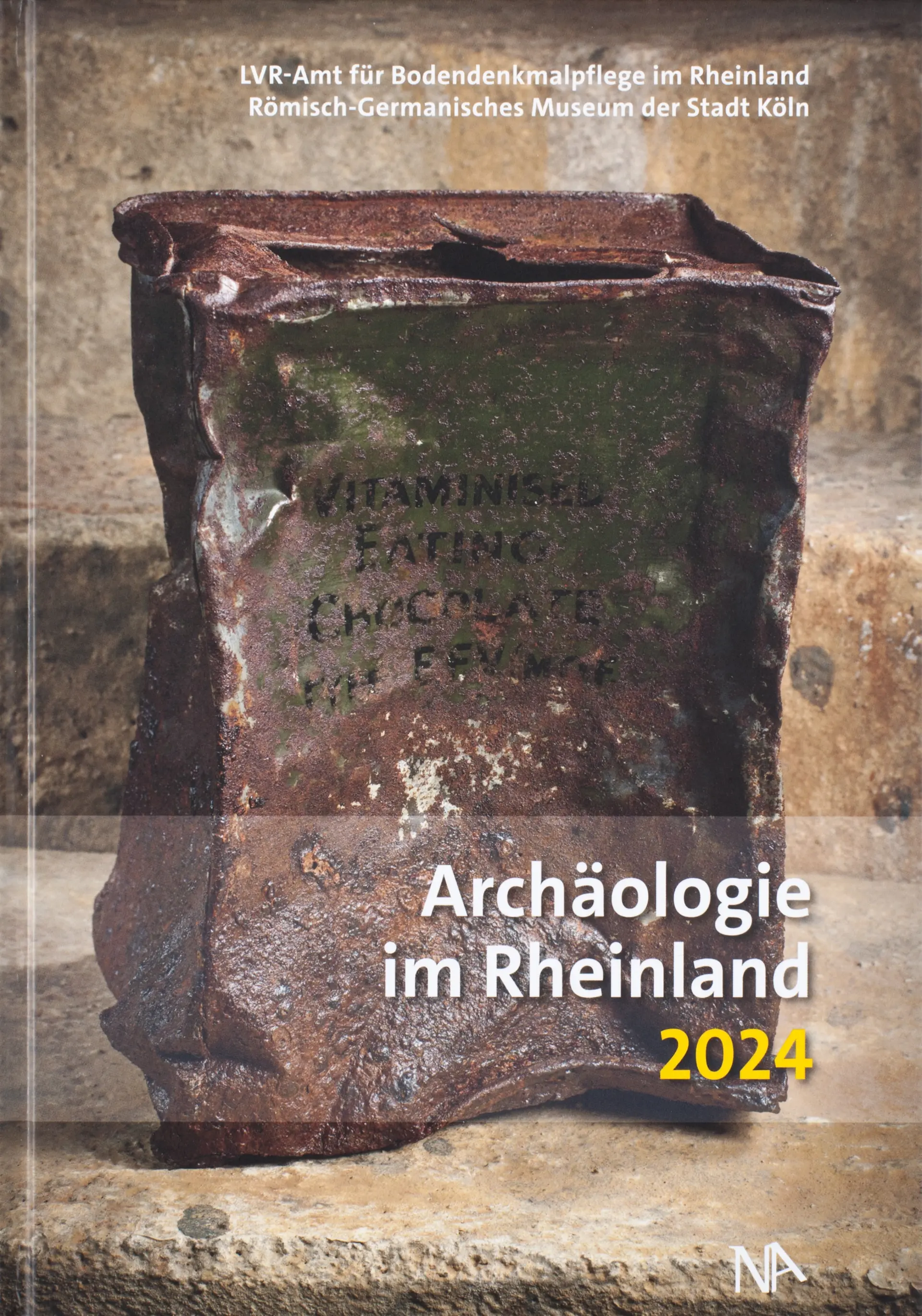 Coverfoto der Archäologie im Rheinland 2024. Das Bild zeigt eine rostige Metallbox mit Aufschrift.