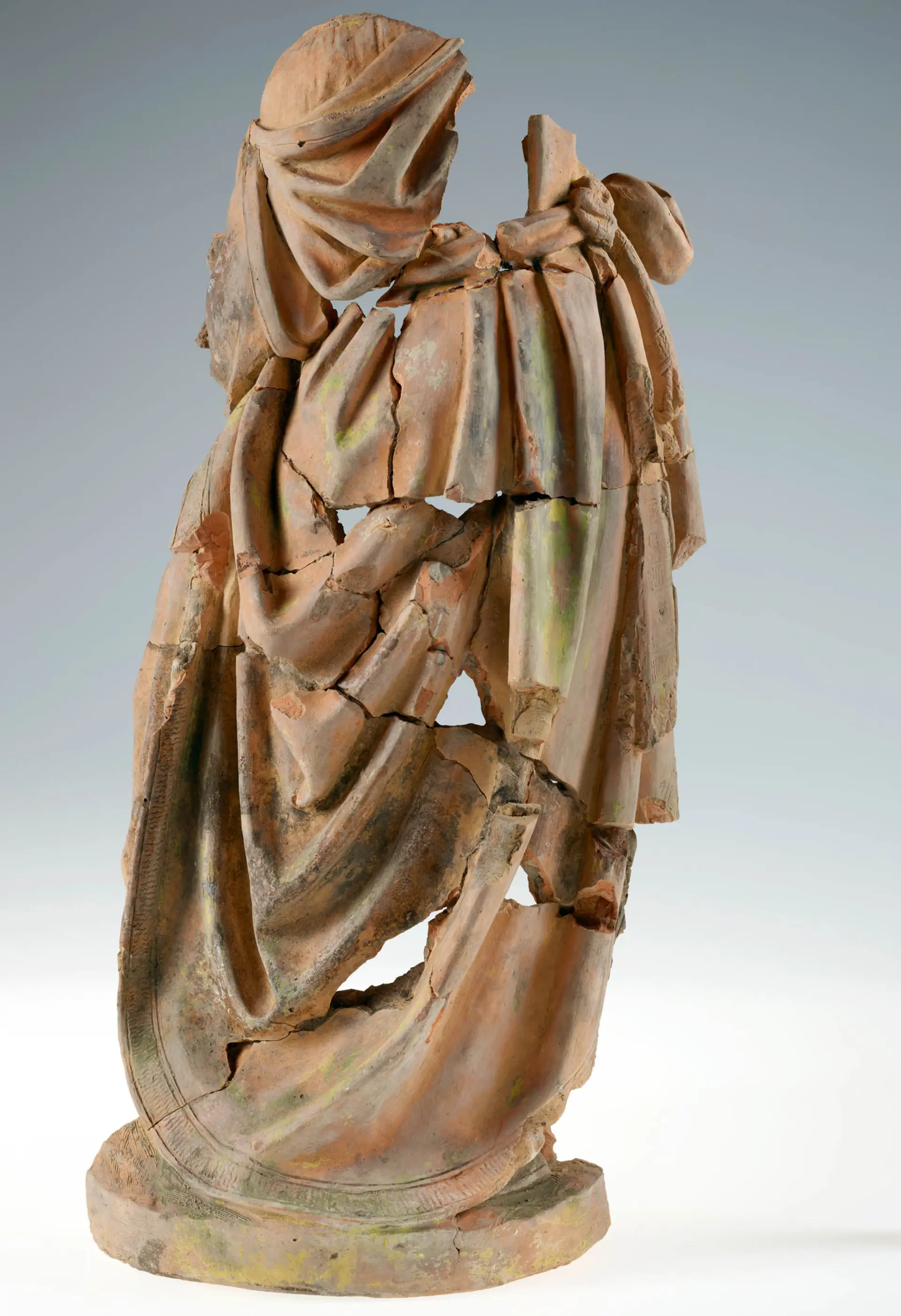 Aufnahme von mehreren bräunlich bis rötlichen Fragmenten, die zu einer Statue zusammengesetzt wurden.