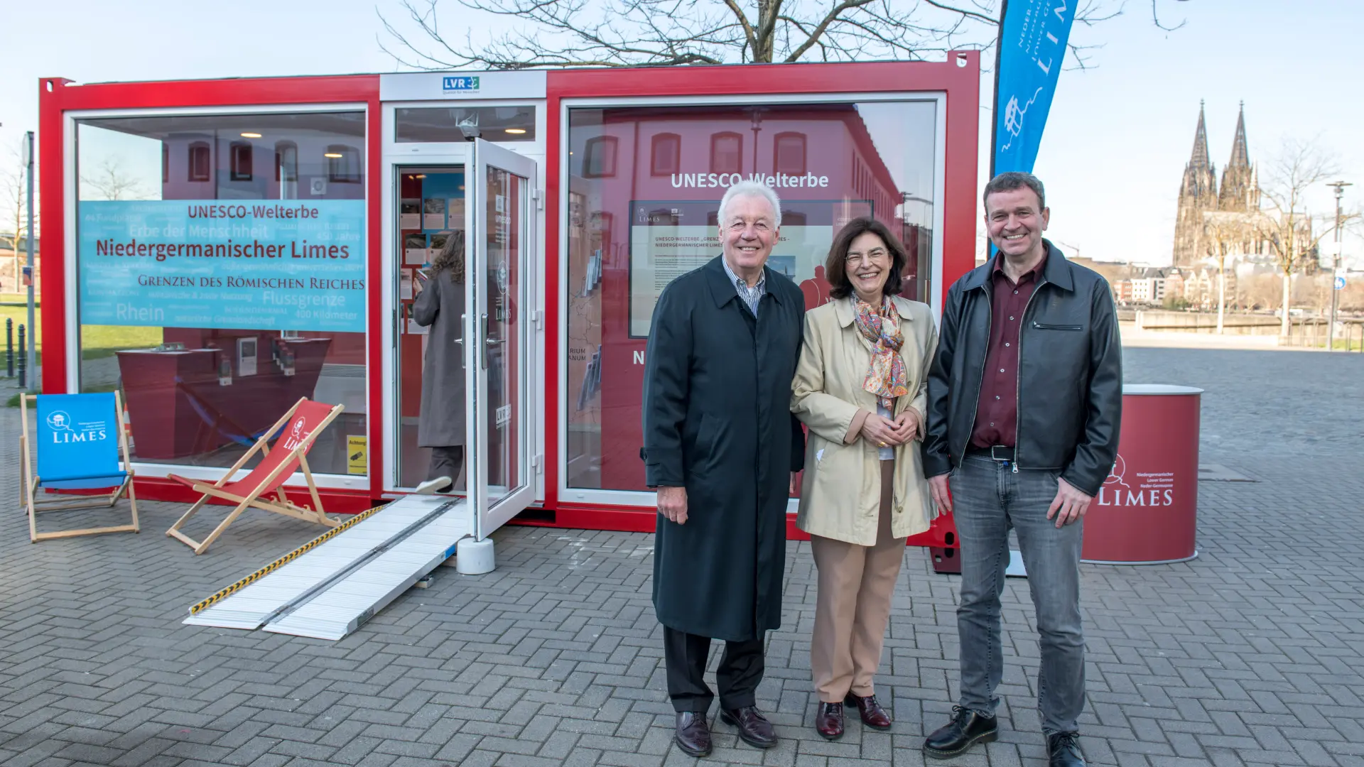 Drei Personen stehen vor einer großen Karte an einer der Containerwände im Innern und diskutieren miteinander.