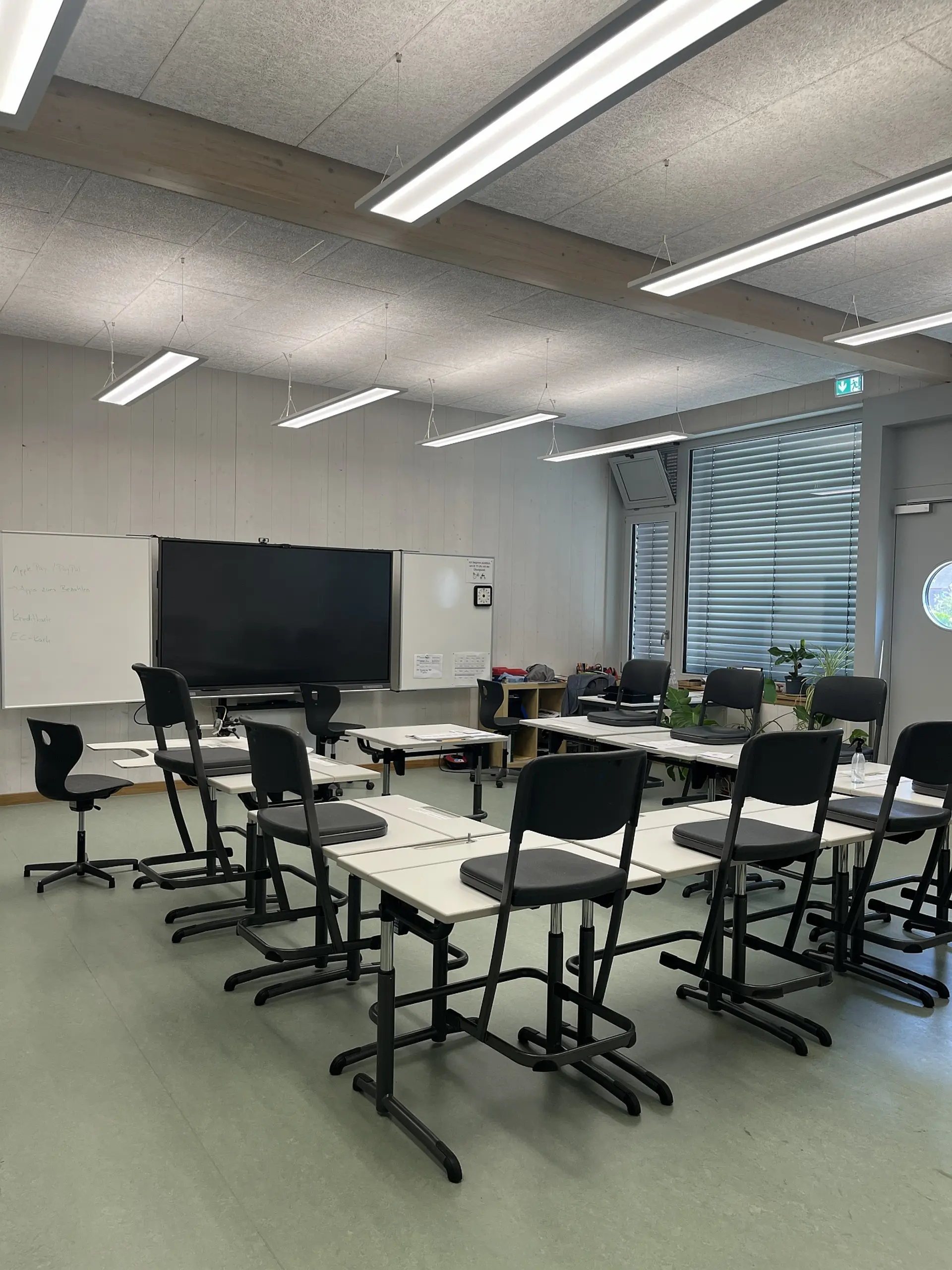 moderner Klassenraum mit höhenverstellbaren Tischen und Smartboard