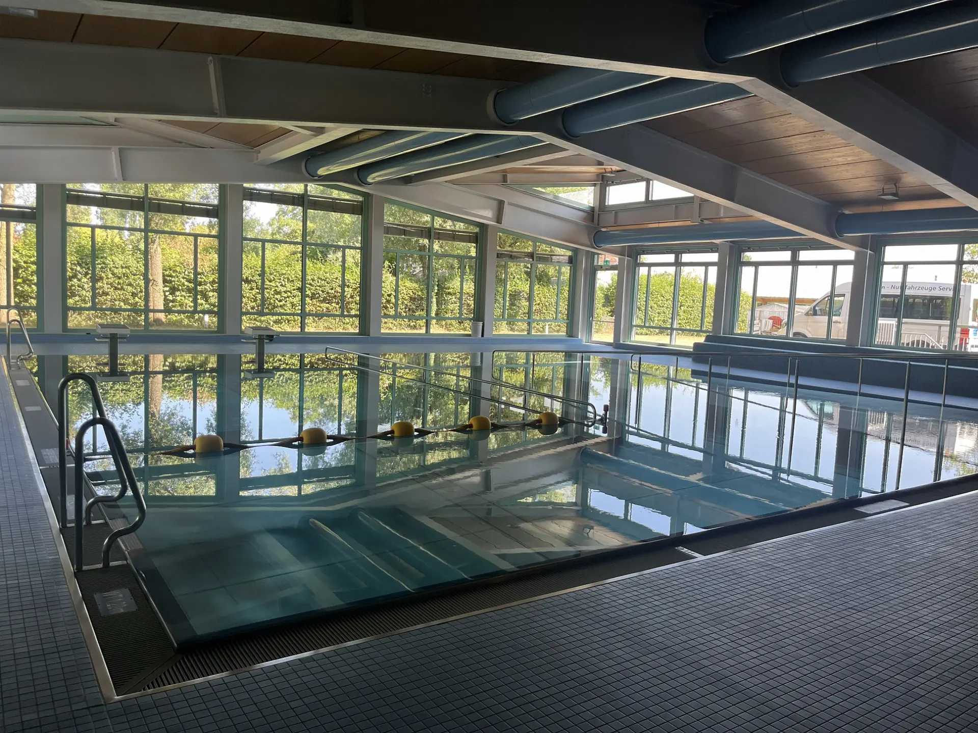 Hallenbad mit großem Becken und Fensterfront mit Blick ins Grüne
