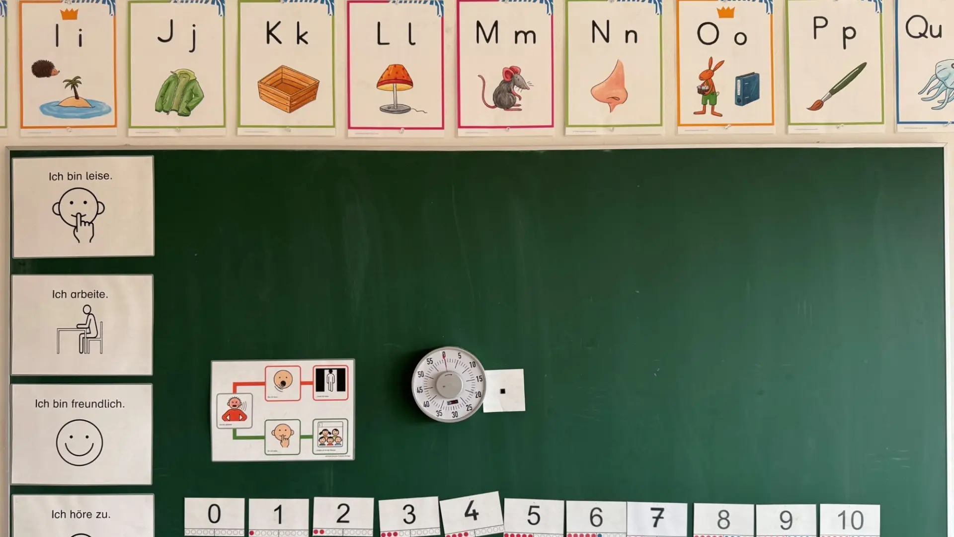 Foto einer grünen Tafel mit Bildkarten für Buchstaben und Zahlen