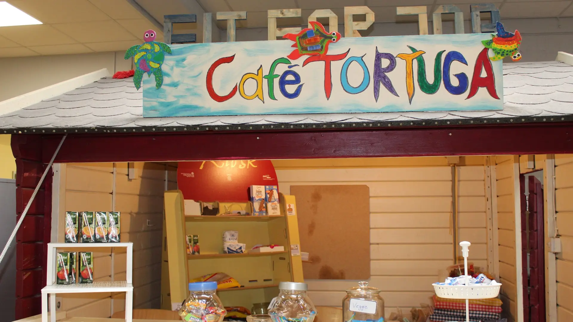 Der Tresen des "Café Tortuga" mit verschiedenen Sachen zum Kaufen und einem bunten Namensschild sowie großen Buchstaben "Fit for Fun"