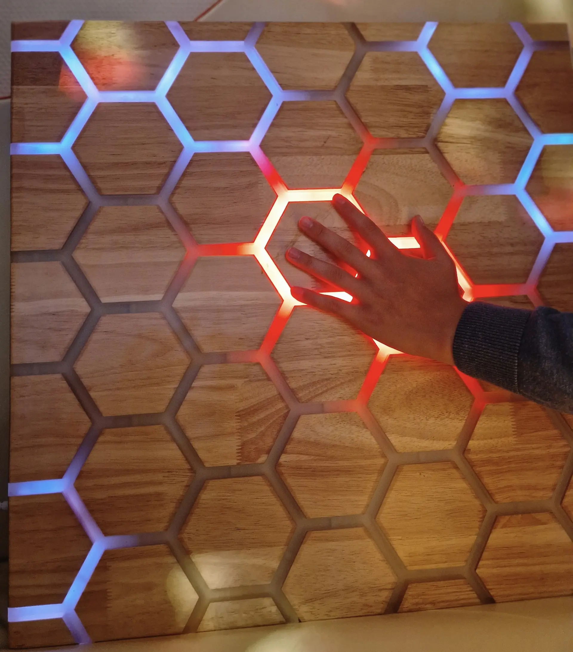 Eine Hand, die ein beleuchtetes Waben-Panel berührt