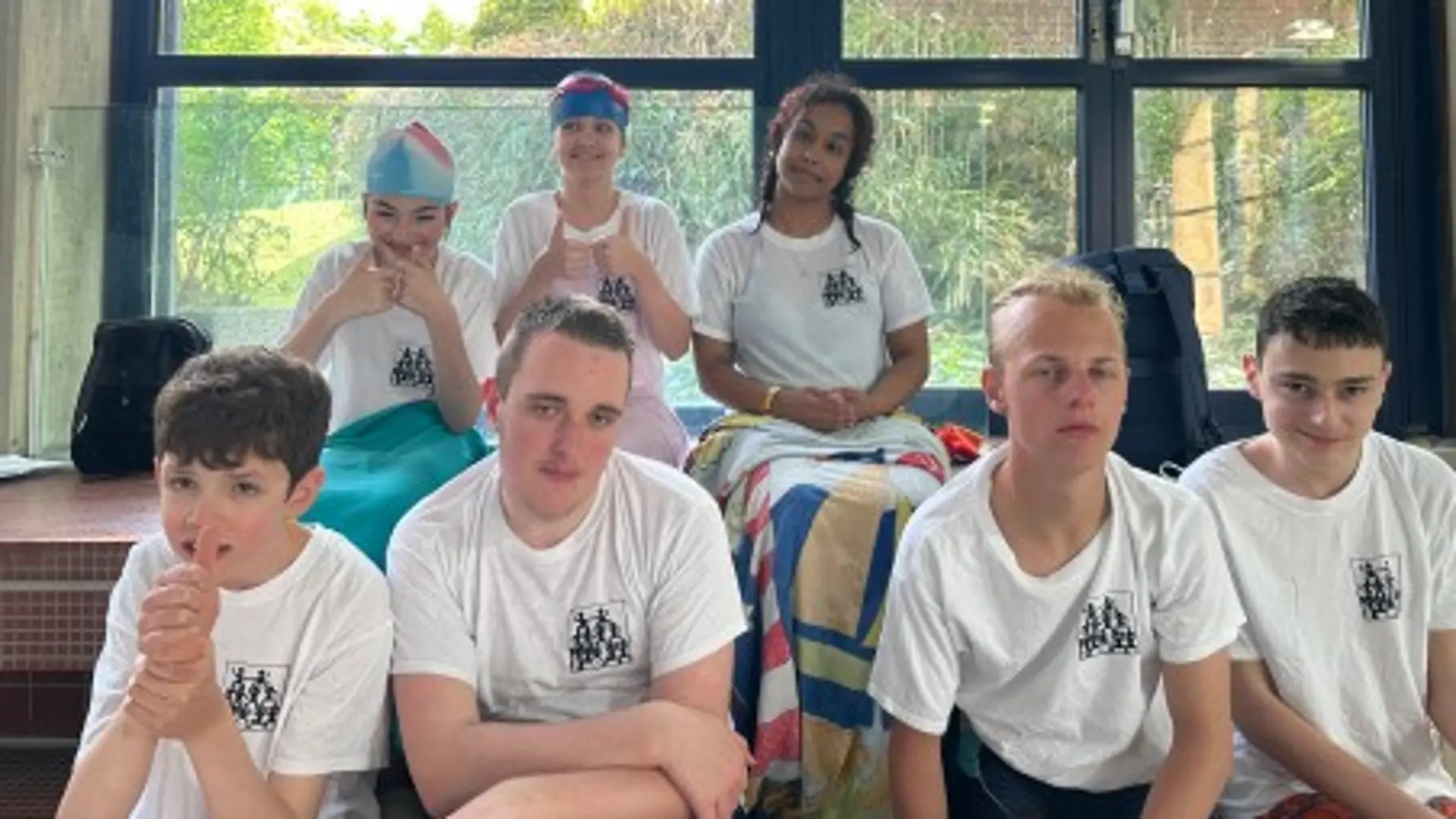 Sieben Schüler*innen in Team-T-Shirts der Schule schauen in die Kamera und lächeln.