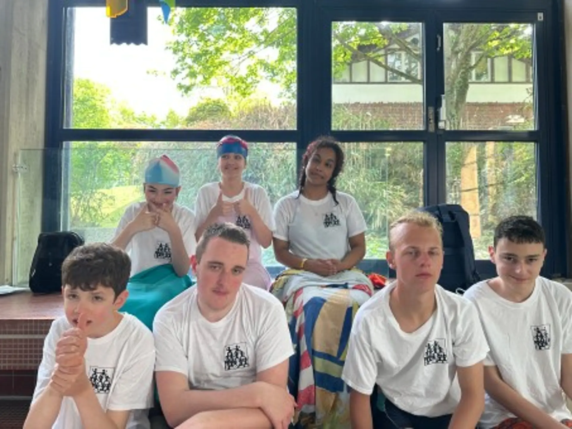 Sieben Schüler*innen in Team-T-Shirts der Schule schauen in die Kamera und lächeln.