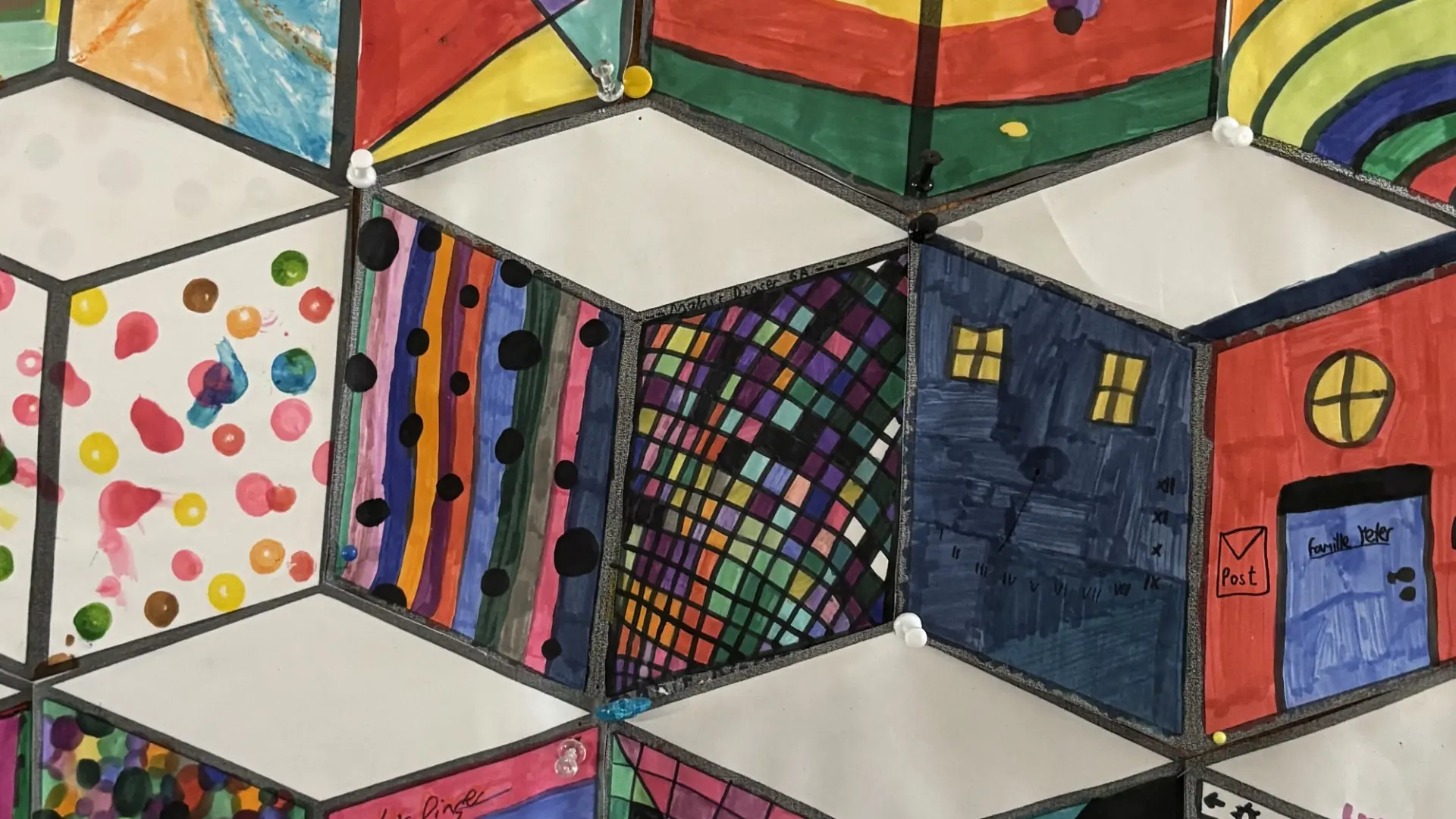 Eine Collage aus vielen gleichgroßen Würfelzeichnungen, die von den Schüler*innen bunt und unterschiedlich ausgemalt wurden.