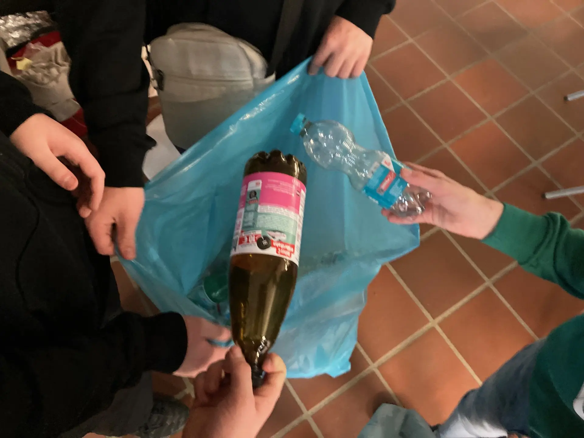 zwei pfandflaschen werden in einen blauen sack gepackt