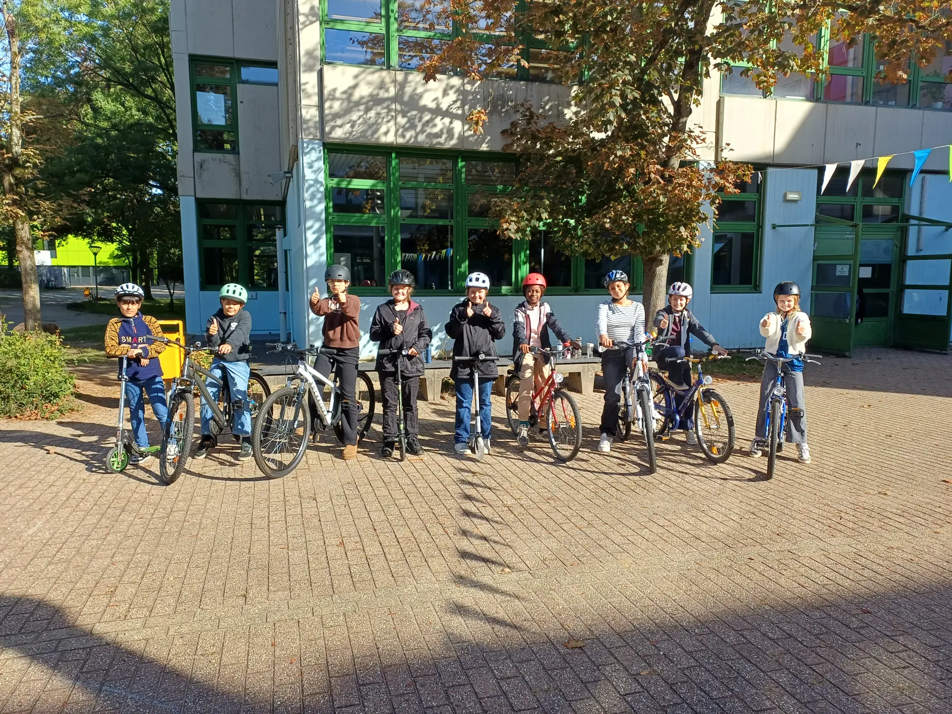 Auf dem Bild ist eine Schülerin der Klasse 4 auf ihrem Fahrrad zu sehen. Sie gibt ein Handzeichen zum Abbiegen