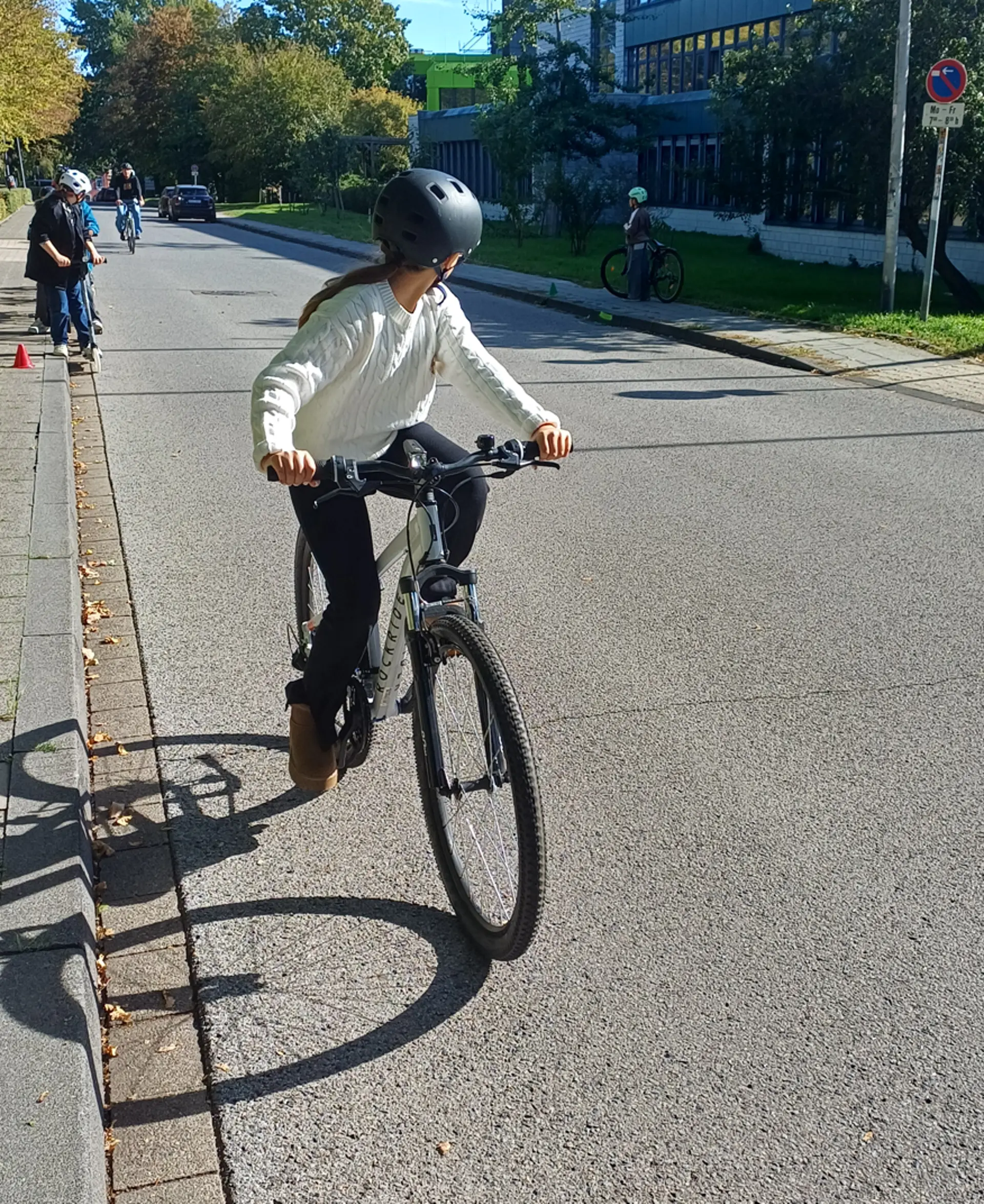 Ein Mädchen der 4. Klasse sitzt auf ihrem Fahrrad und macht einen Schulterblick um sich umzusehen. 