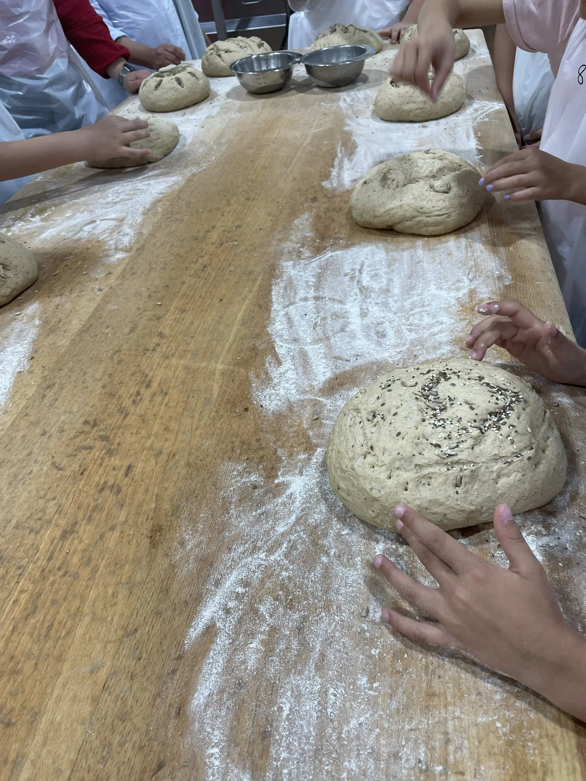 Brot-Rohlinge werden mit Saaten und Einkerbungen verziert.