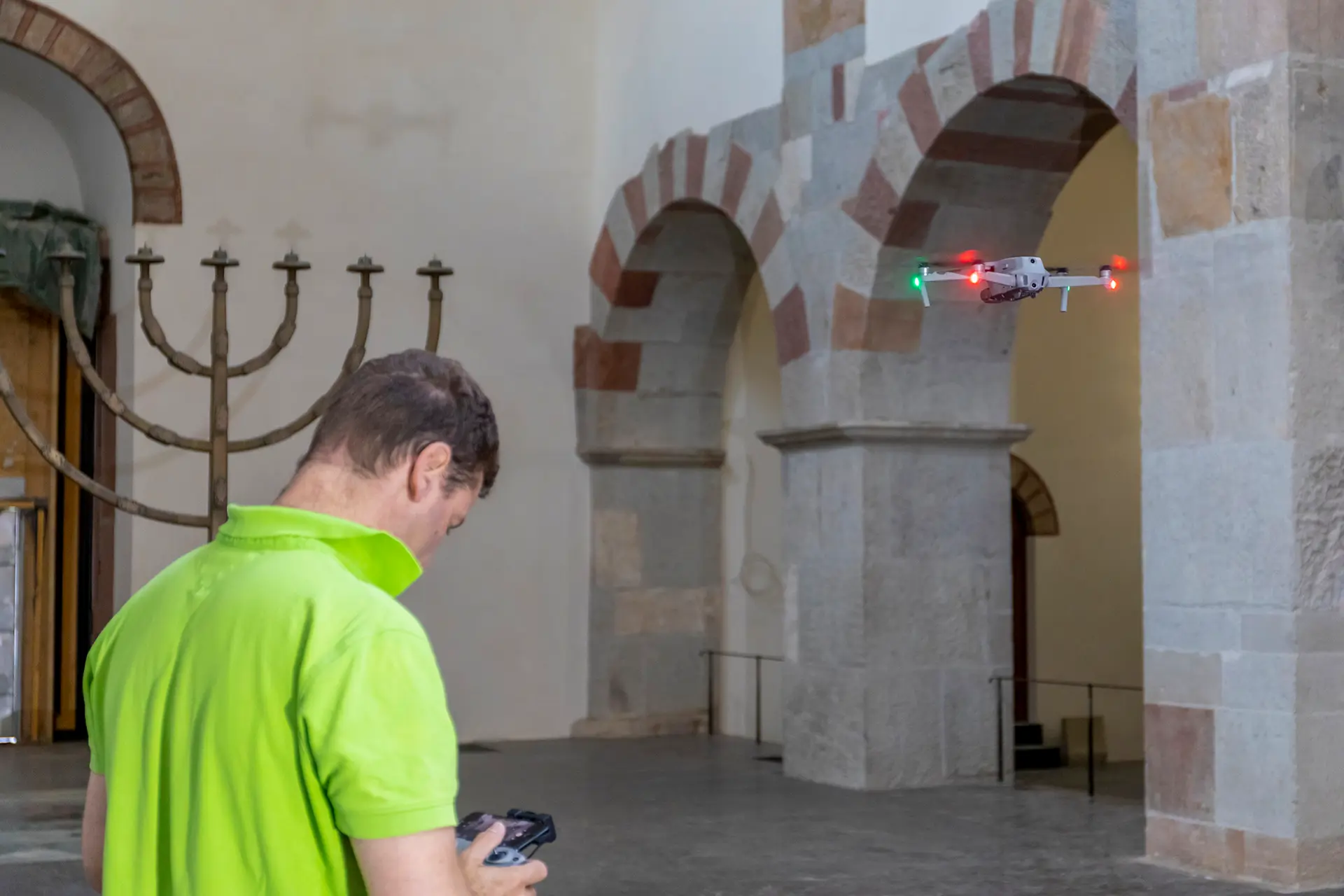 Mitarbeiter steuert Drohne in einer Kirche für Bauaufnahme. 