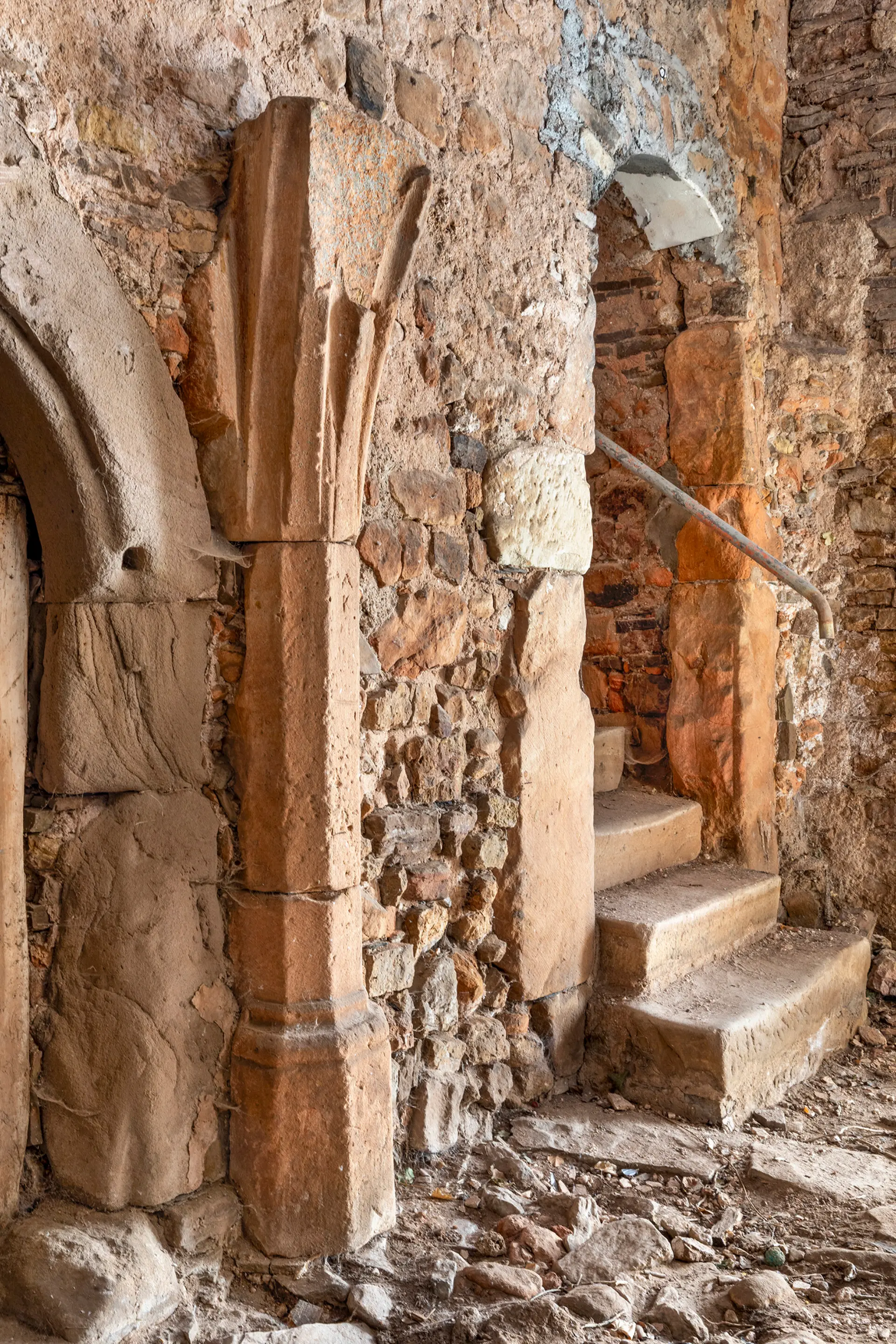 Gewölbesaal einer Burganlage, vorne Rundbogenportal und Säule aus Sandstein. 
