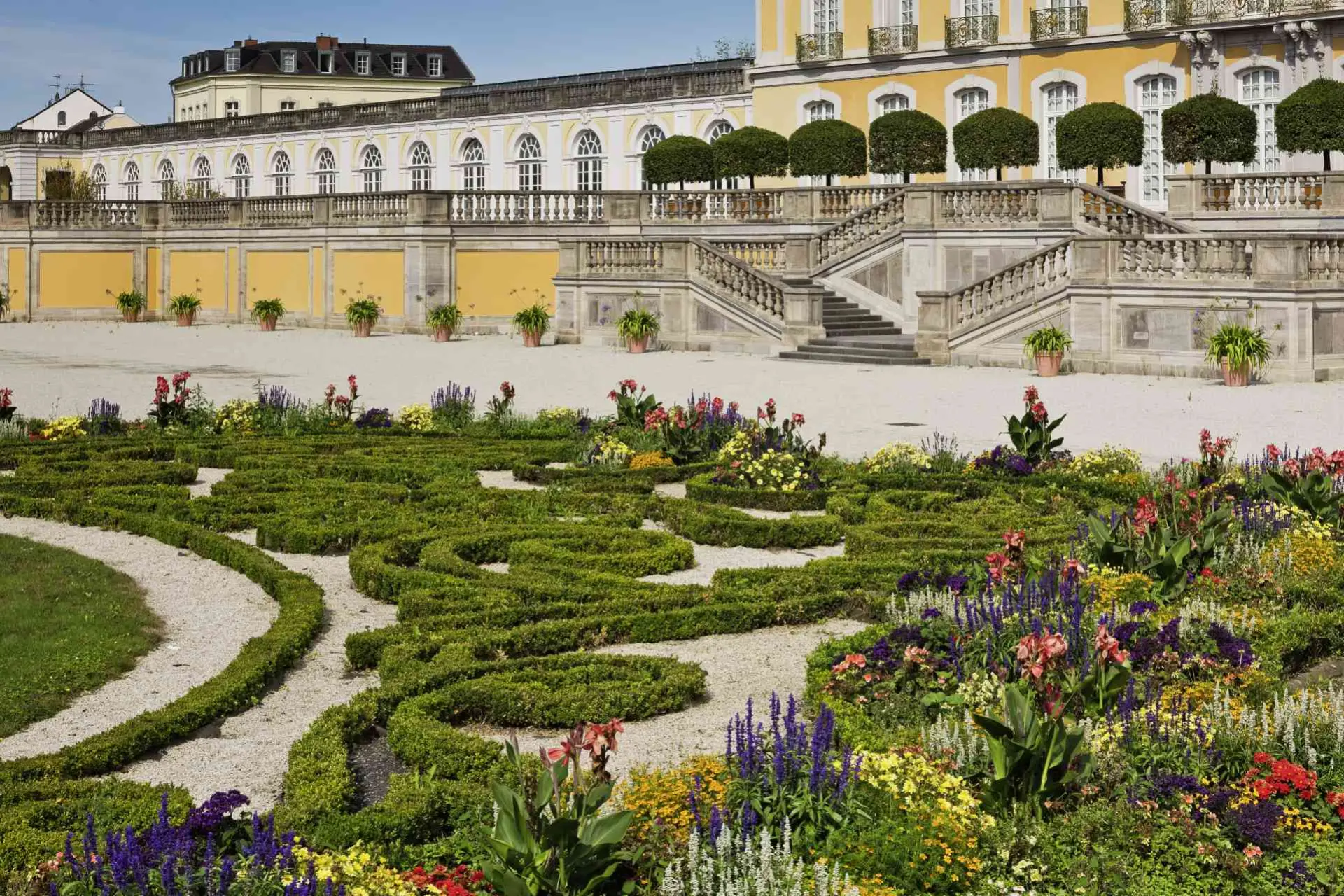 Ansicht des Brühler Schlossparks mit südlicher Orangerie im Hintergrund, Schlossterrasse, Parterregarten und Blumenrabatten. 