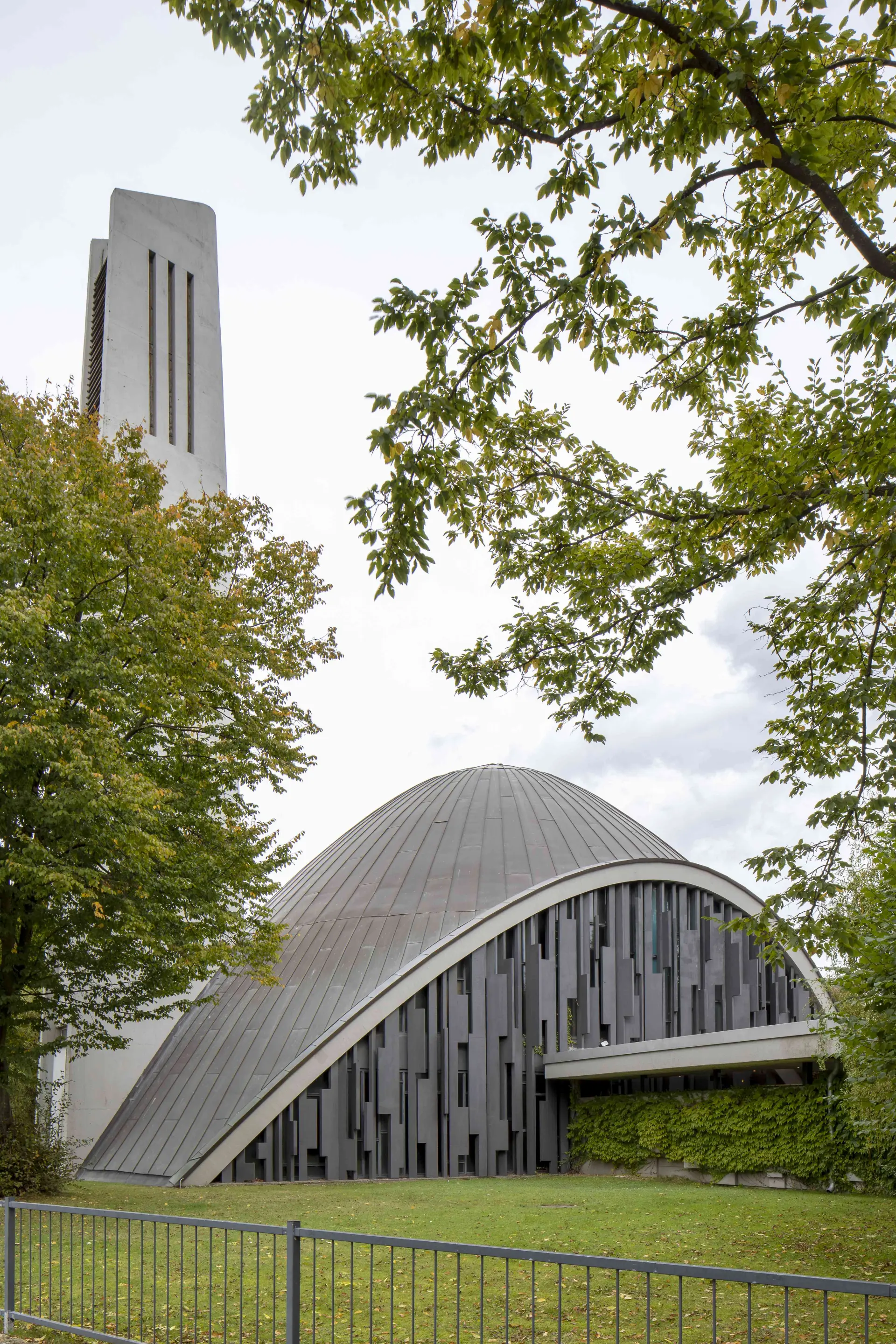 Nachkriegskirche mit bogenförmigem Dach und Kirchturm. 