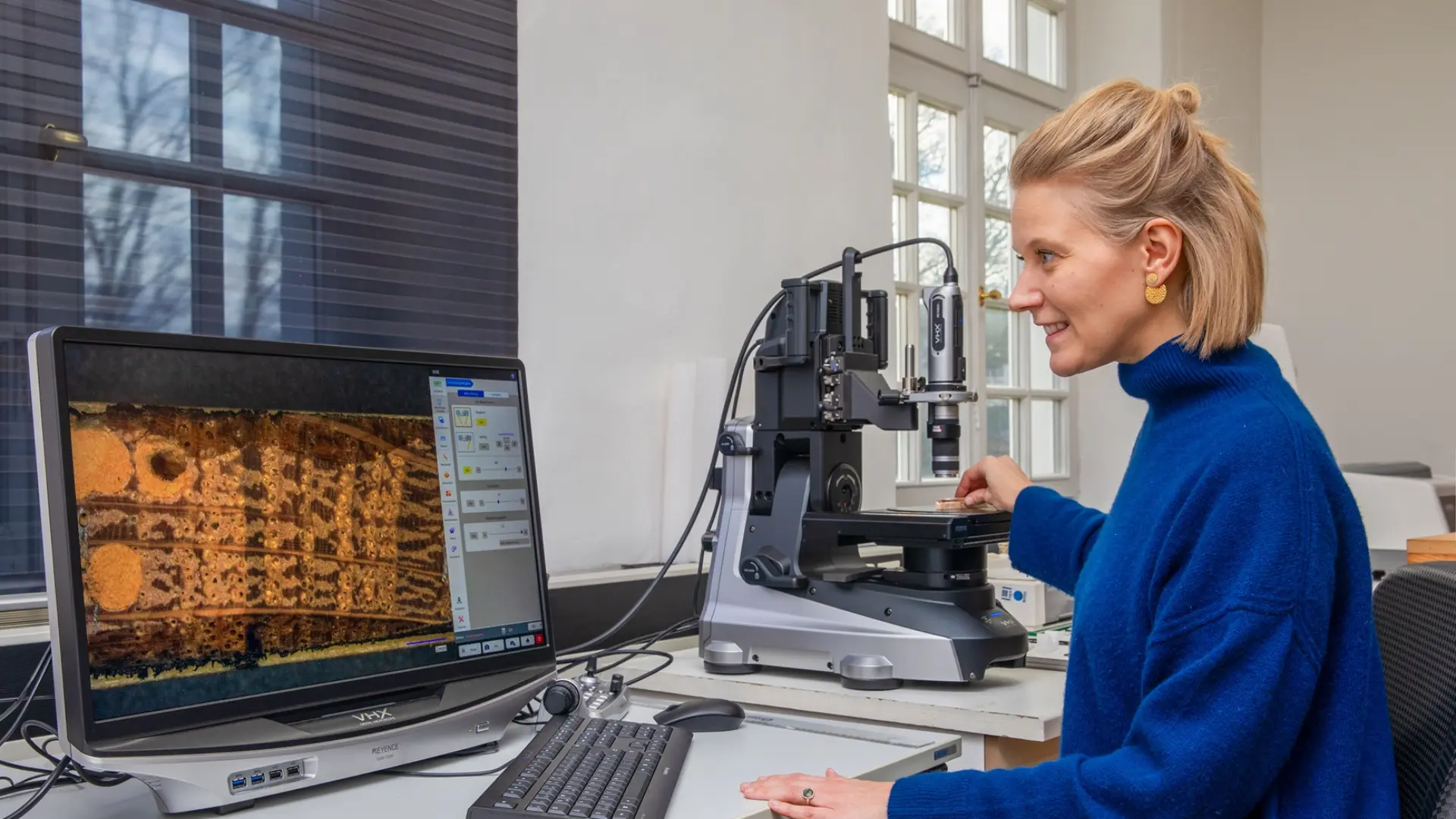 Mitarbeiterin misst am Computerbildschirm die Jahrringe einer Holzprobe aus