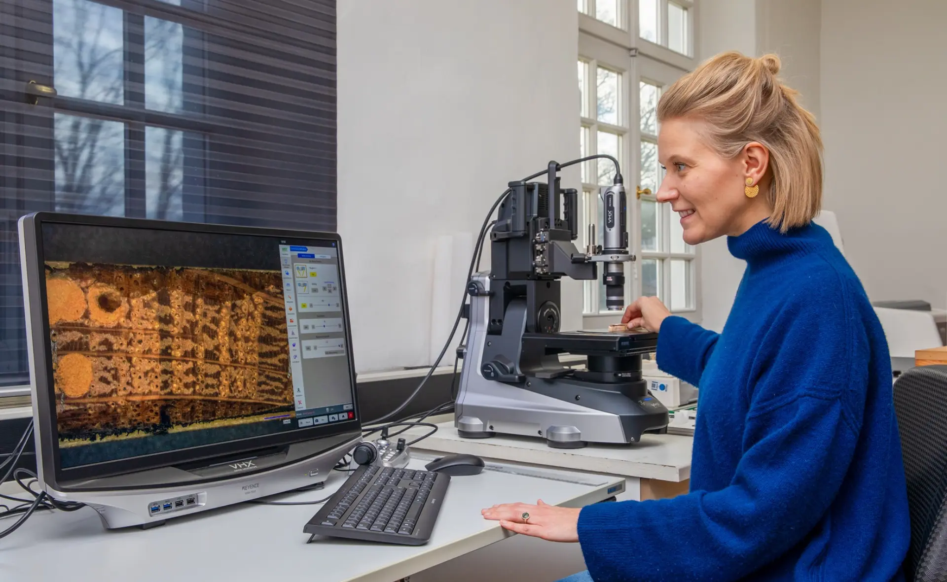 Mitarbeiterin misst am Computerbildschirm die Jahrringe einer Holzprobe aus
