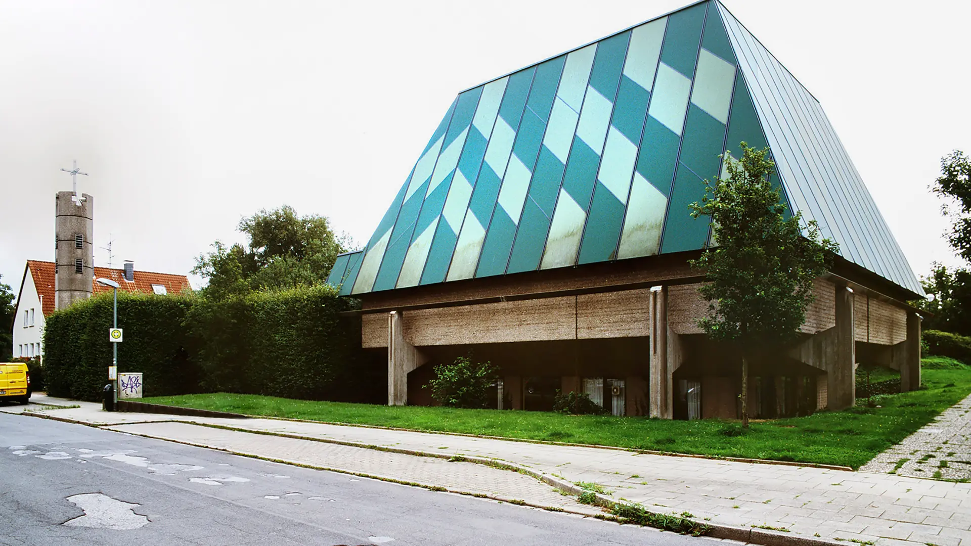 Außenansicht eines modernen Kirchenbaus aus Beton mit hoch aufragendem pyramidalem Dach 