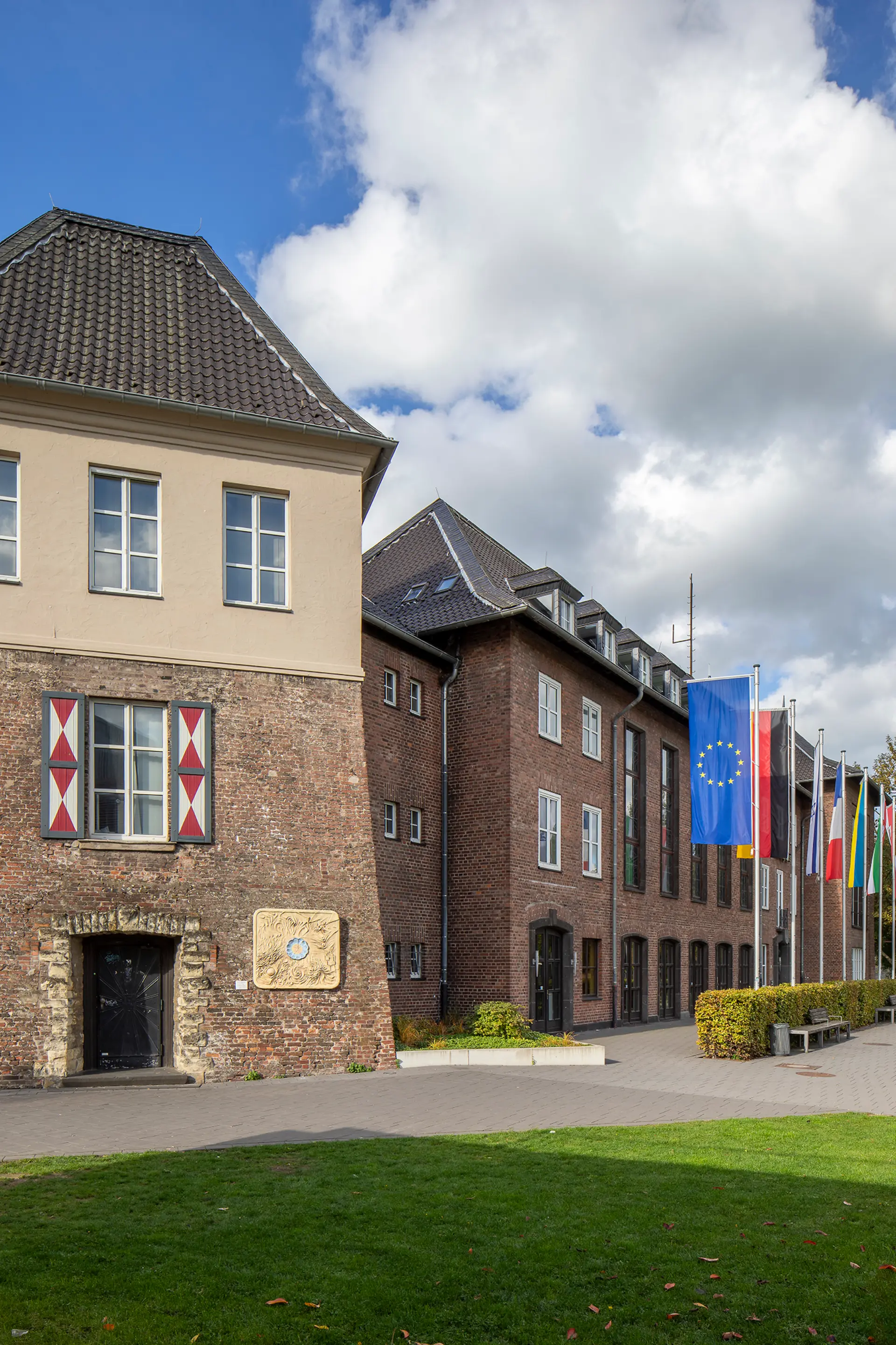 mehrstöckiges Gebäude mit Eckturm und davor gehissten Fahnen