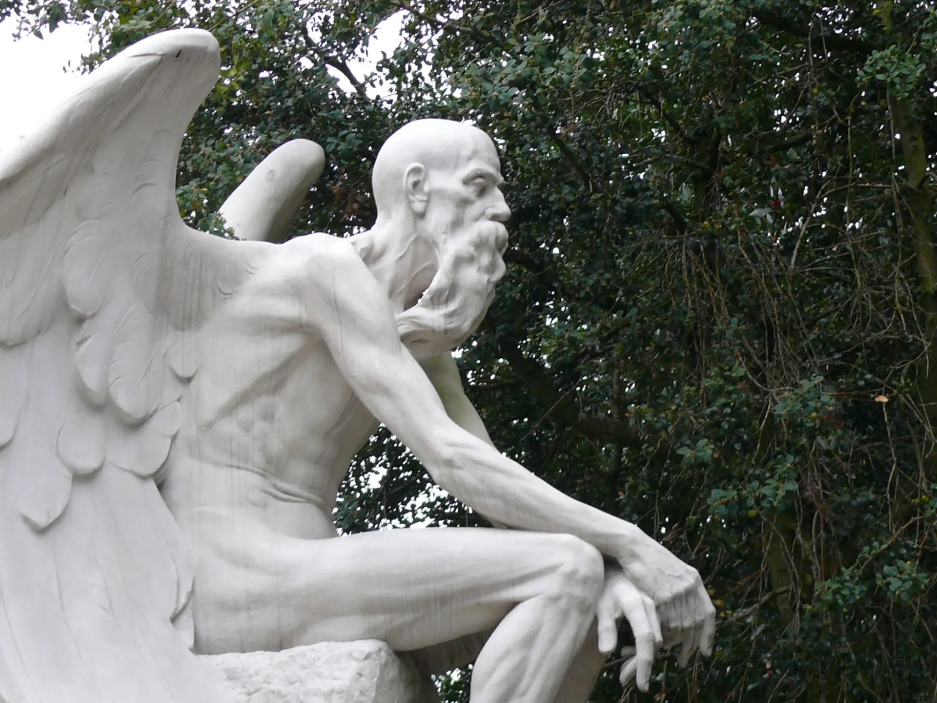 Statue eines sitzenden geflügelten bärtigen Gottes