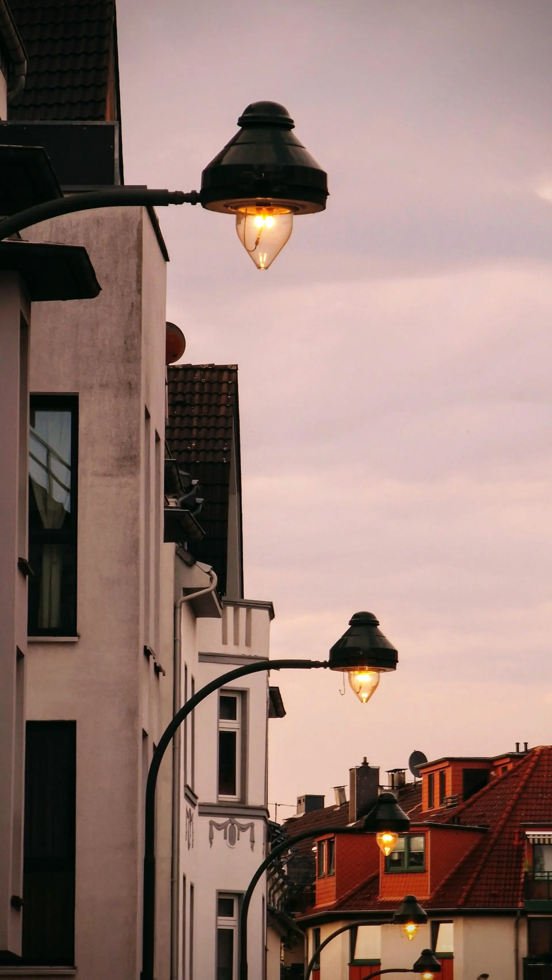 Gebogene Leuchten erhellen mit ihrem warmen Licht einen Straßenzug.