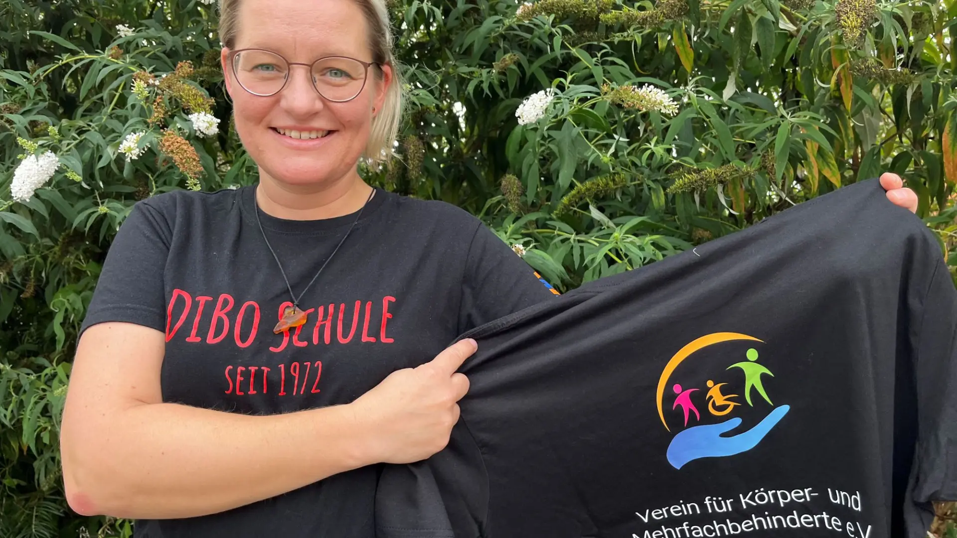 Eine Frau zeigt ein schwarzes T-Shirt mit dem Logo des Fördervereins