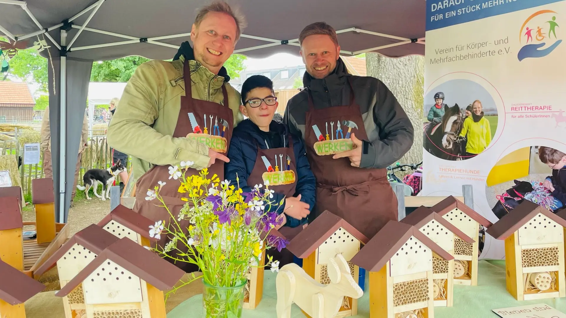 Kleine Insektenhotels werden an einem Stand von zwei Erwachsenen und einem Kind zum Verkauf angeboten.