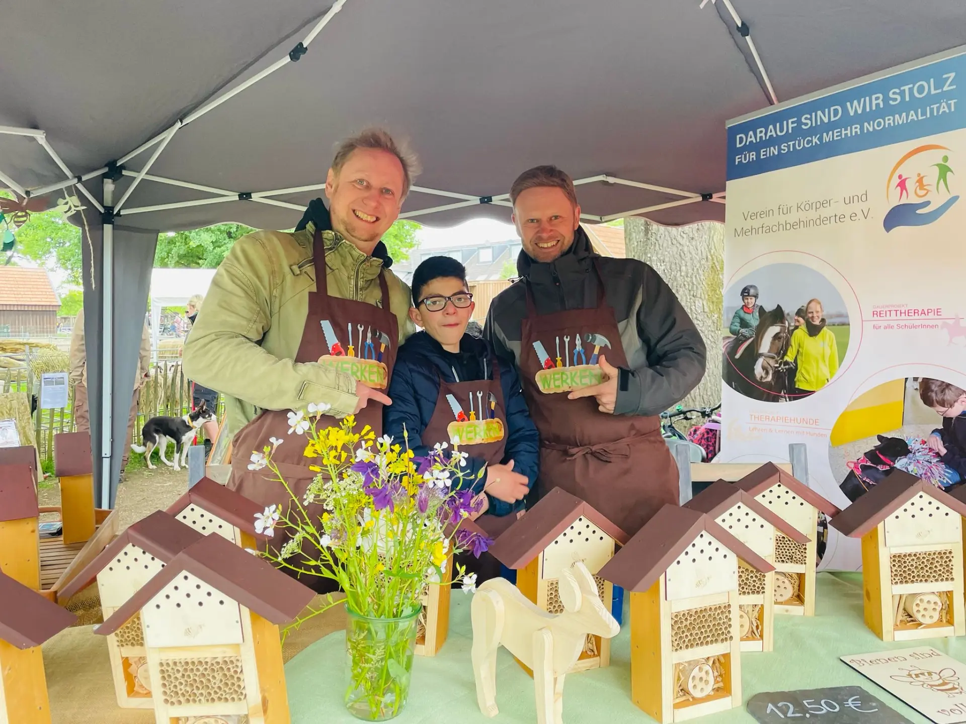 Kleine Insektenhotels werden an einem Stand von zwei Erwachsenen und einem Kind zum Verkauf angeboten.