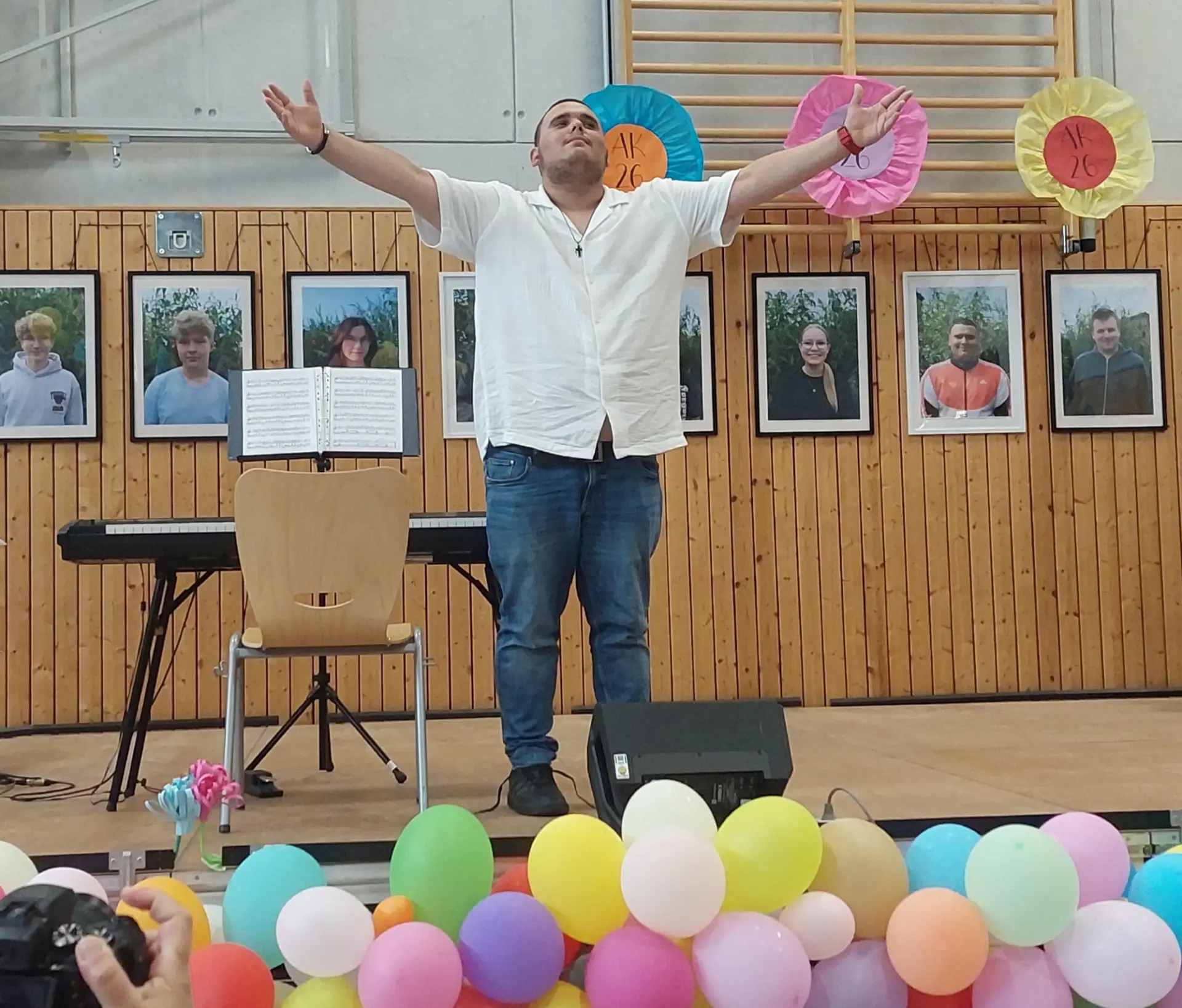 Ein junger Mann steht auf einer Bühne - im Hintergrund ein E-Piano- und nimmt mit ausgebreiteten Armen Applaus entgegen