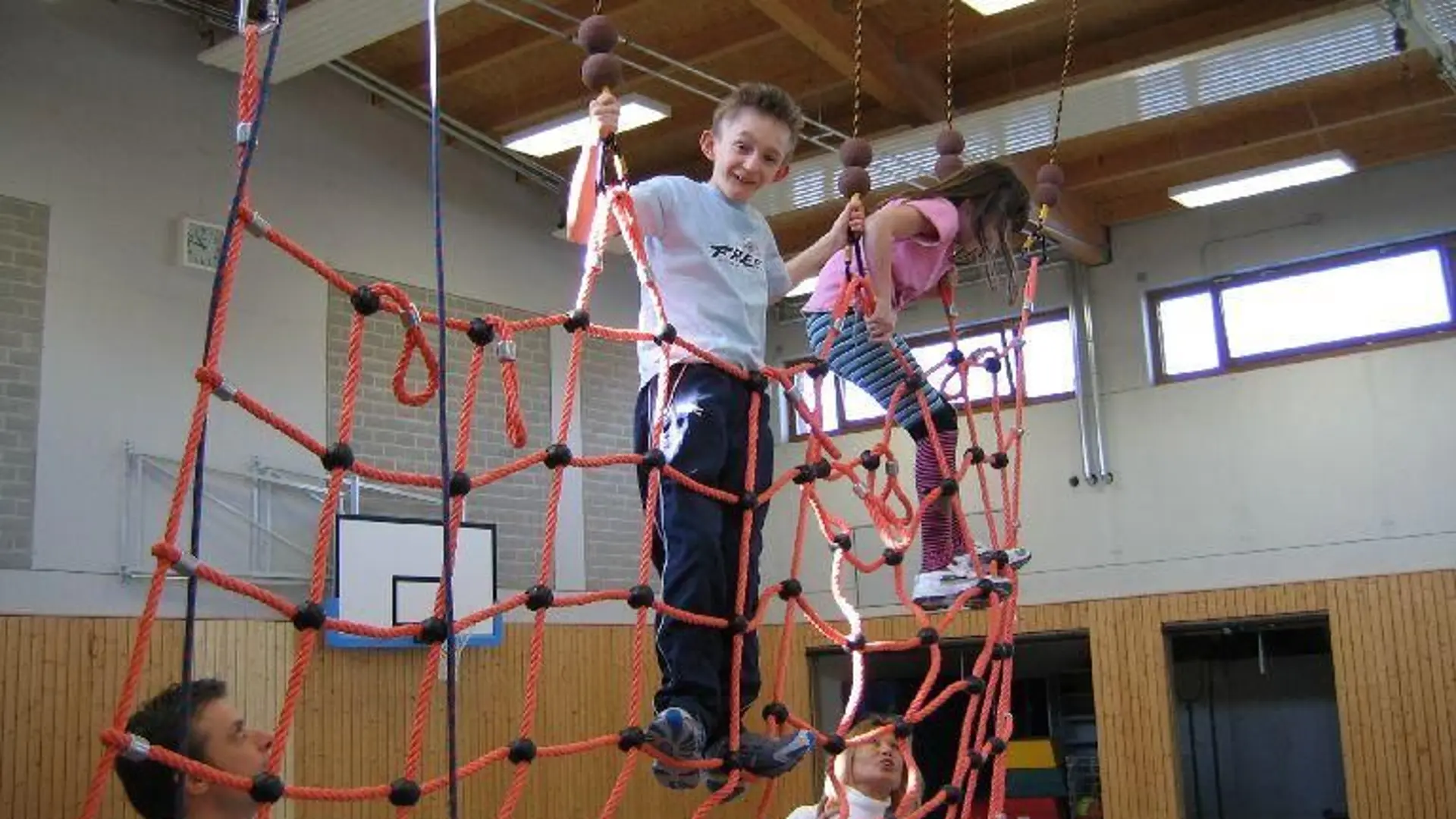 Kinder klettern in einer Turnhalle in einem Kletternetz